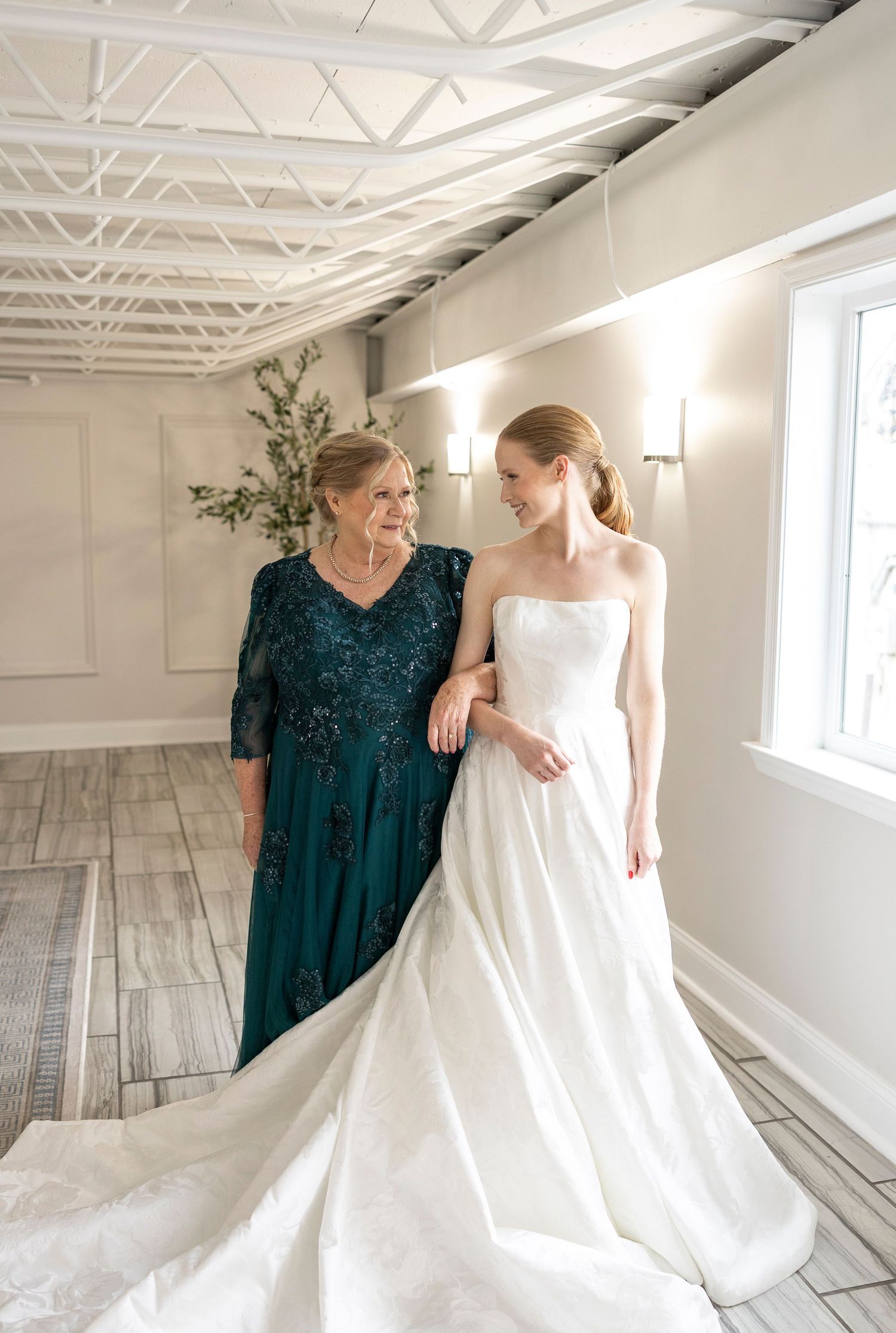 A heartwarming moment between two people as they prepare in a bright studio with a wedding dress.