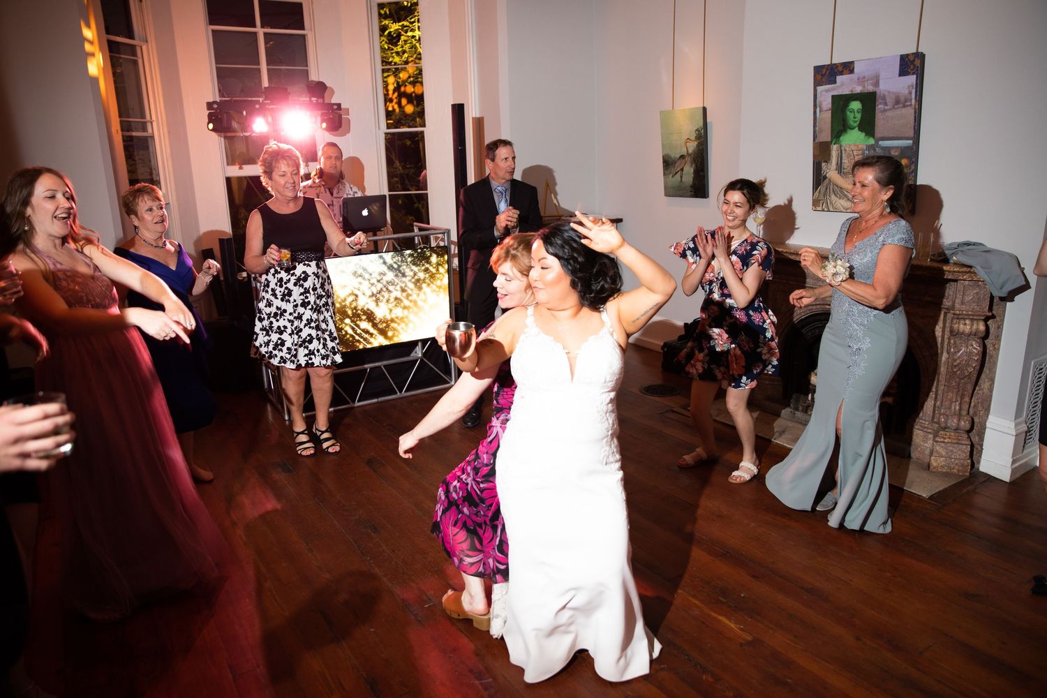 Wedding reception dance party with guests celebrating on a wooden dance floor under string lights.