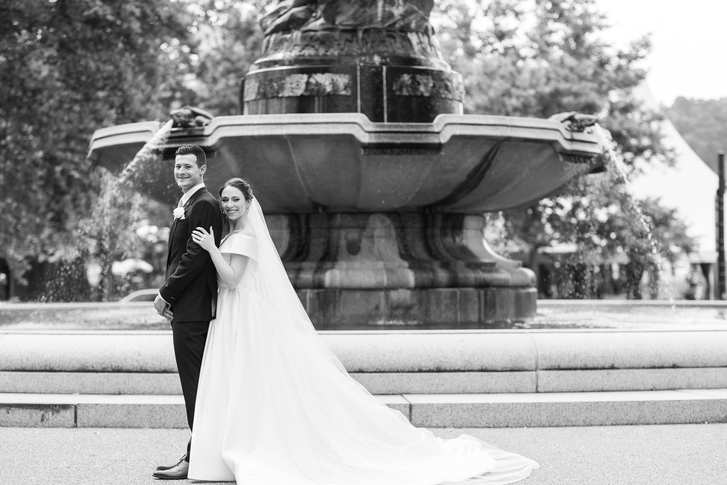Black and white wedding portraits taken near a historic fountain.