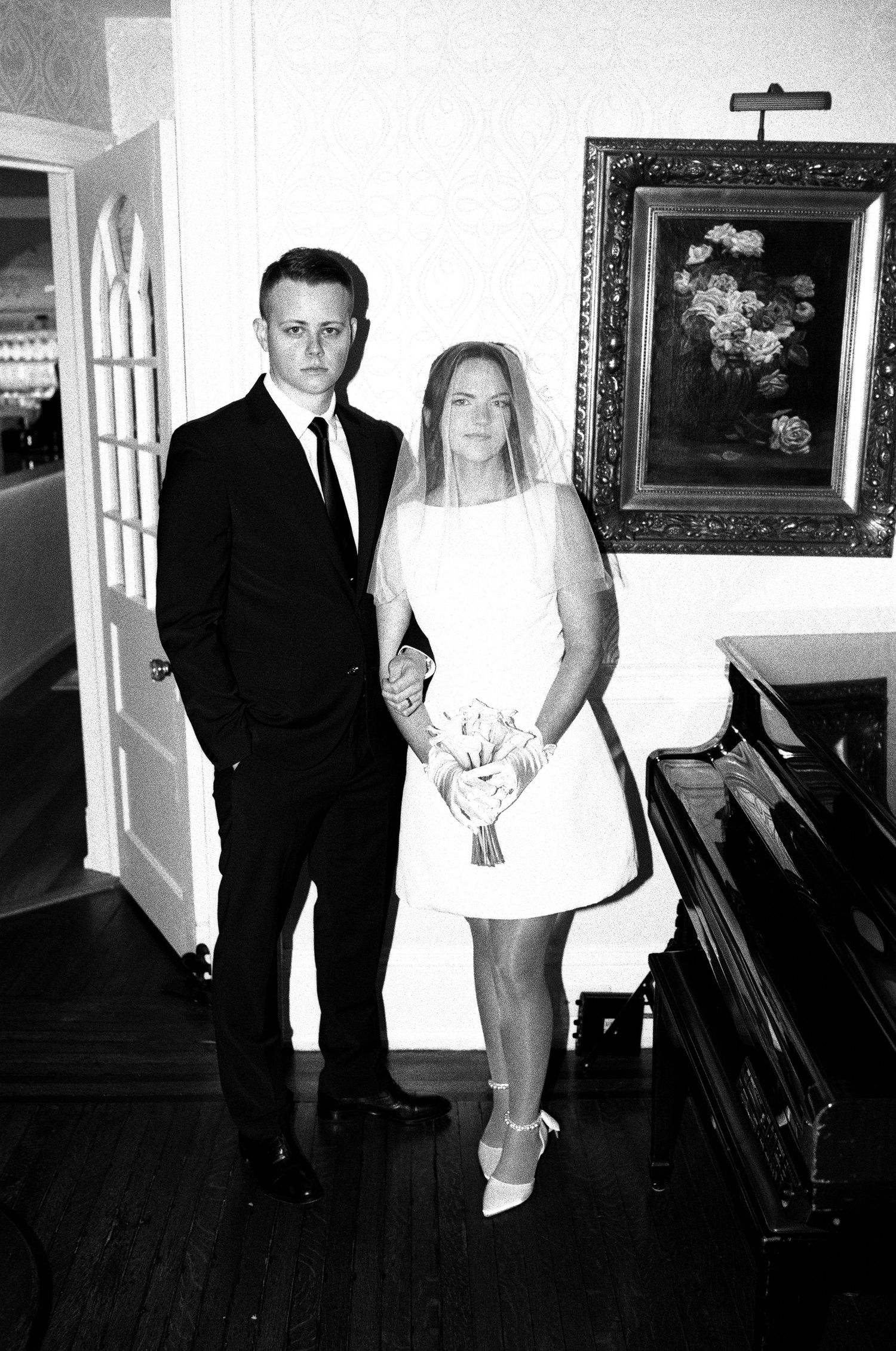 Elegant black and white wedding portraits showing couple posing in formal interior setting.