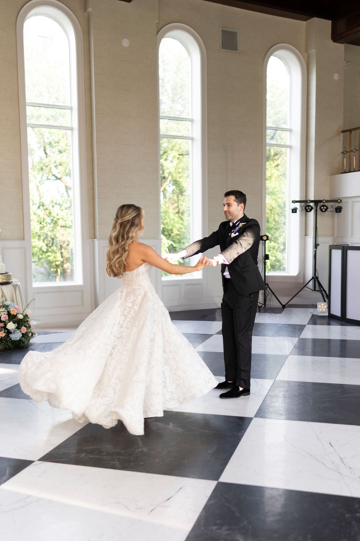 Wedding dance sequence on black and white checkered ballroom floor with arched windows.