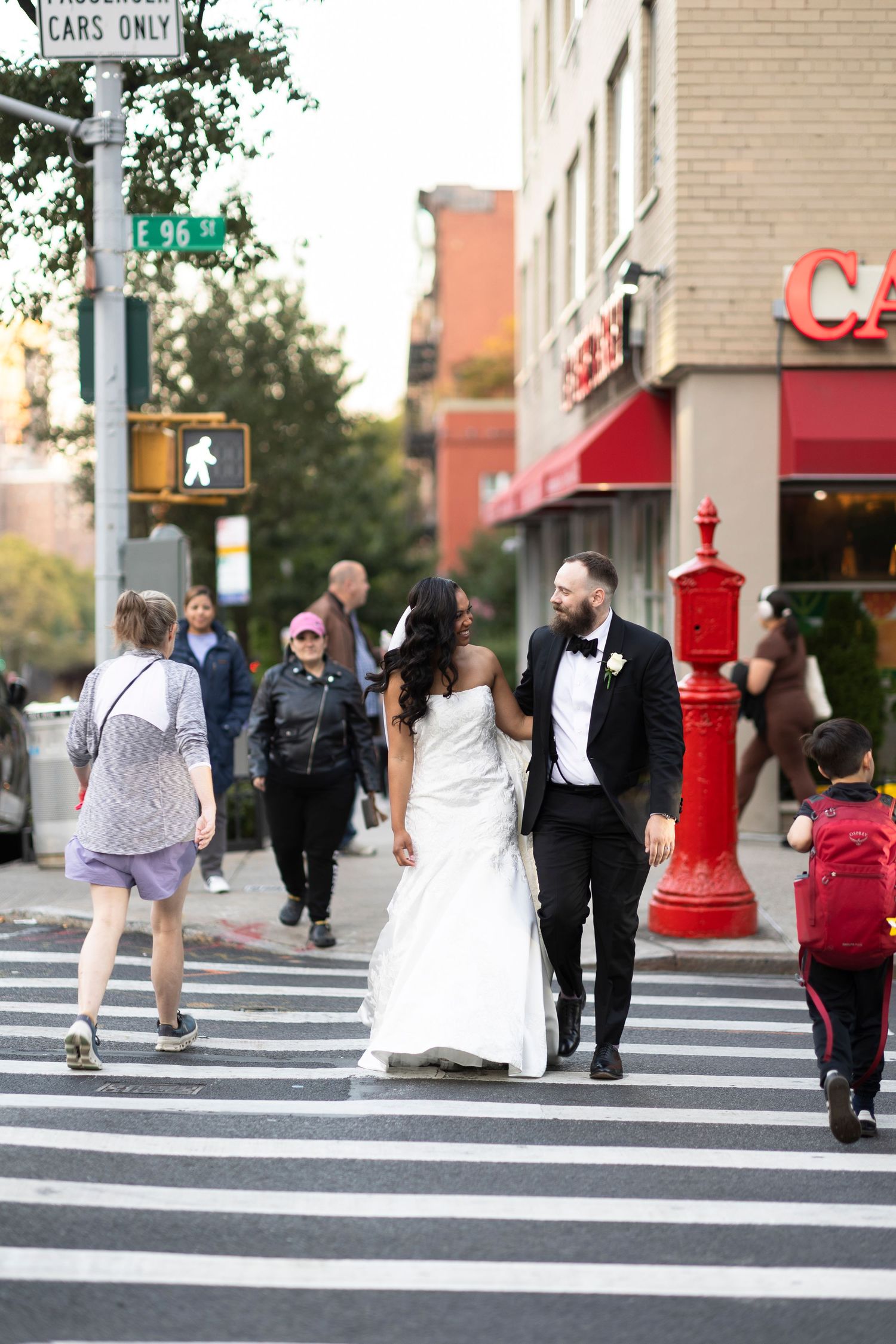 Wedding couple crossing a city street with urban buildings in the background.