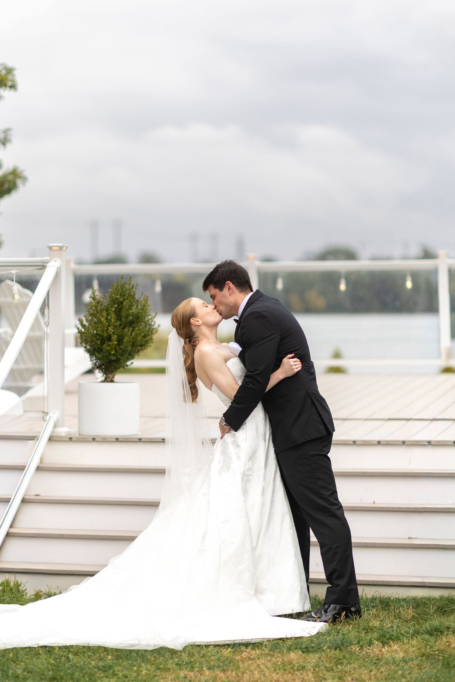 Romantic wedding ceremony moment captured on a waterfront deck with white railings.