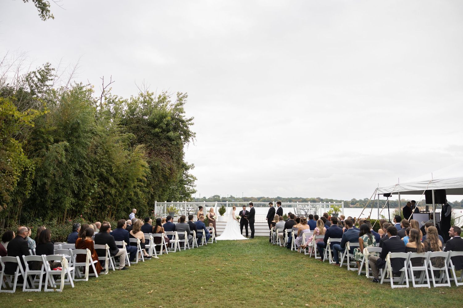 An outdoor wedding ceremony setup with white chairs overlooking a waterfront view.
