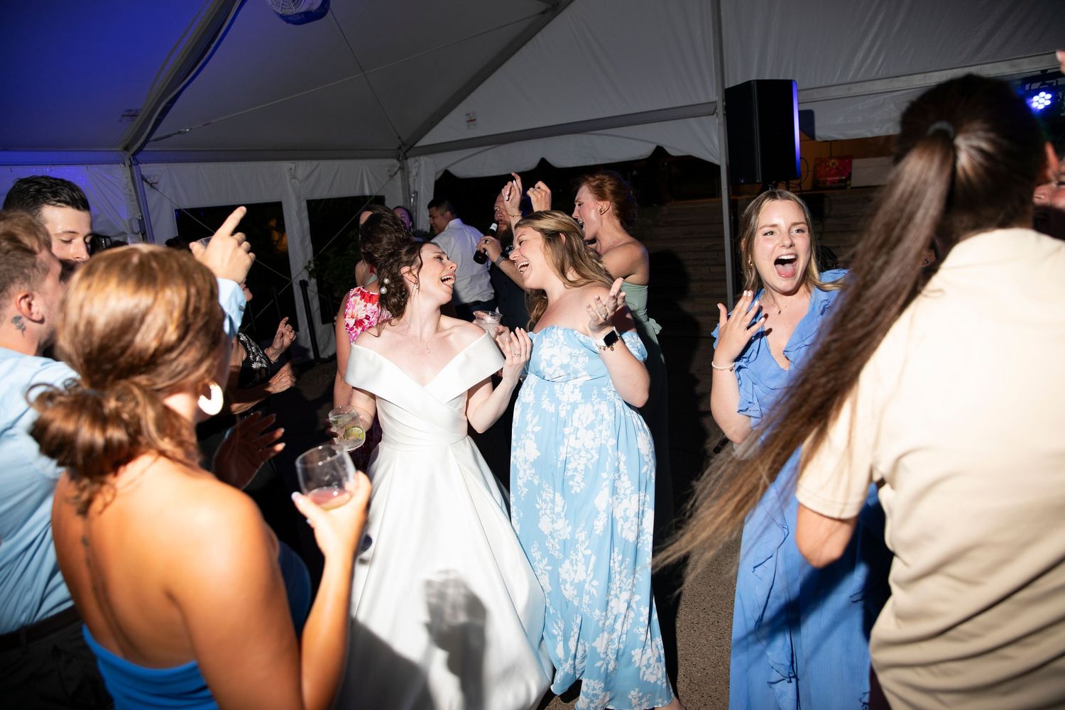 Lively dance party scene with guests celebrating under blue ambient lighting.