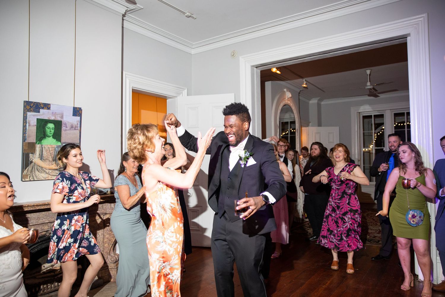 People dancing and mingling at a festive indoor wedding reception.