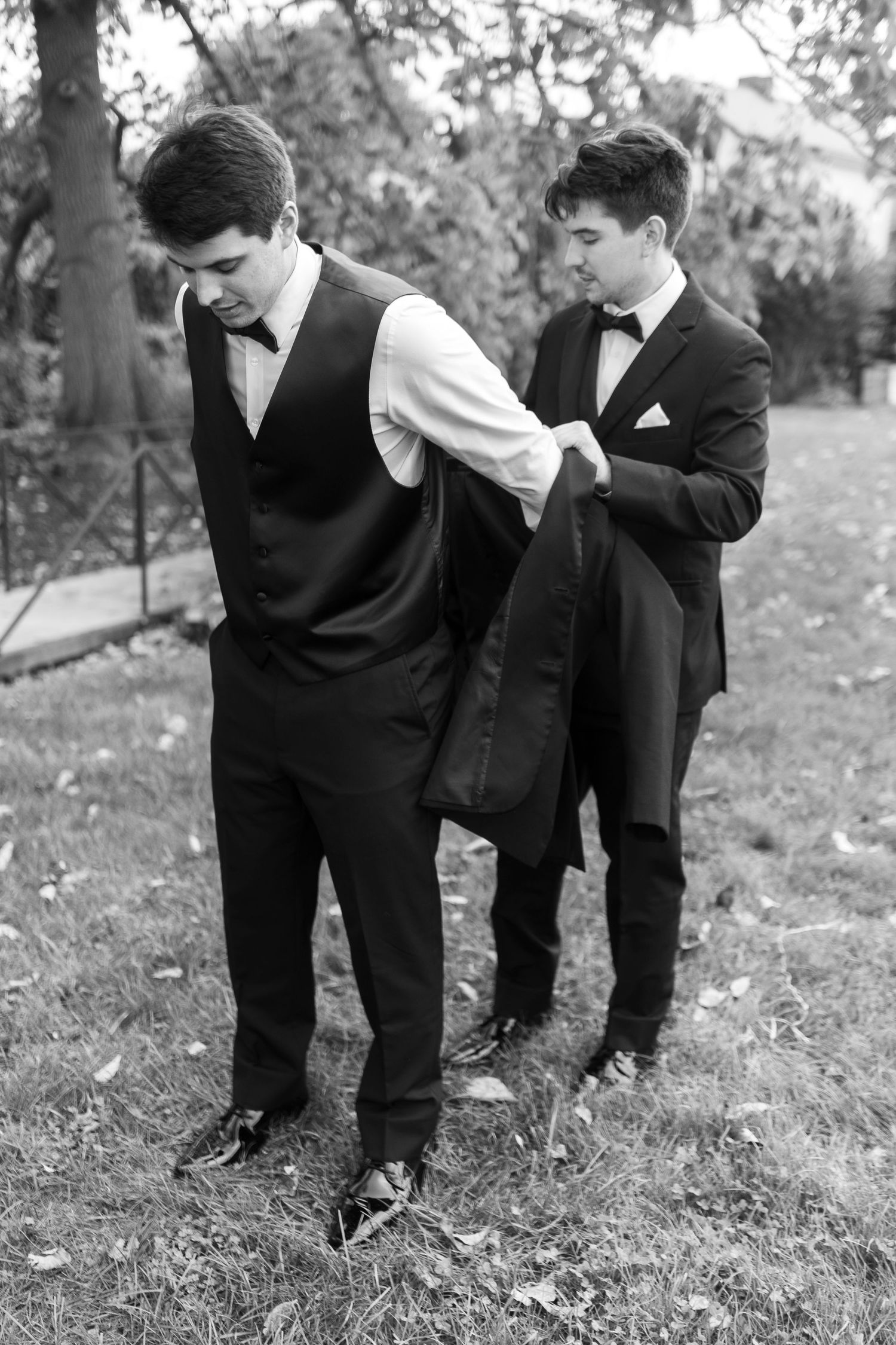 Black and white photo of formal wear adjustment between two people.