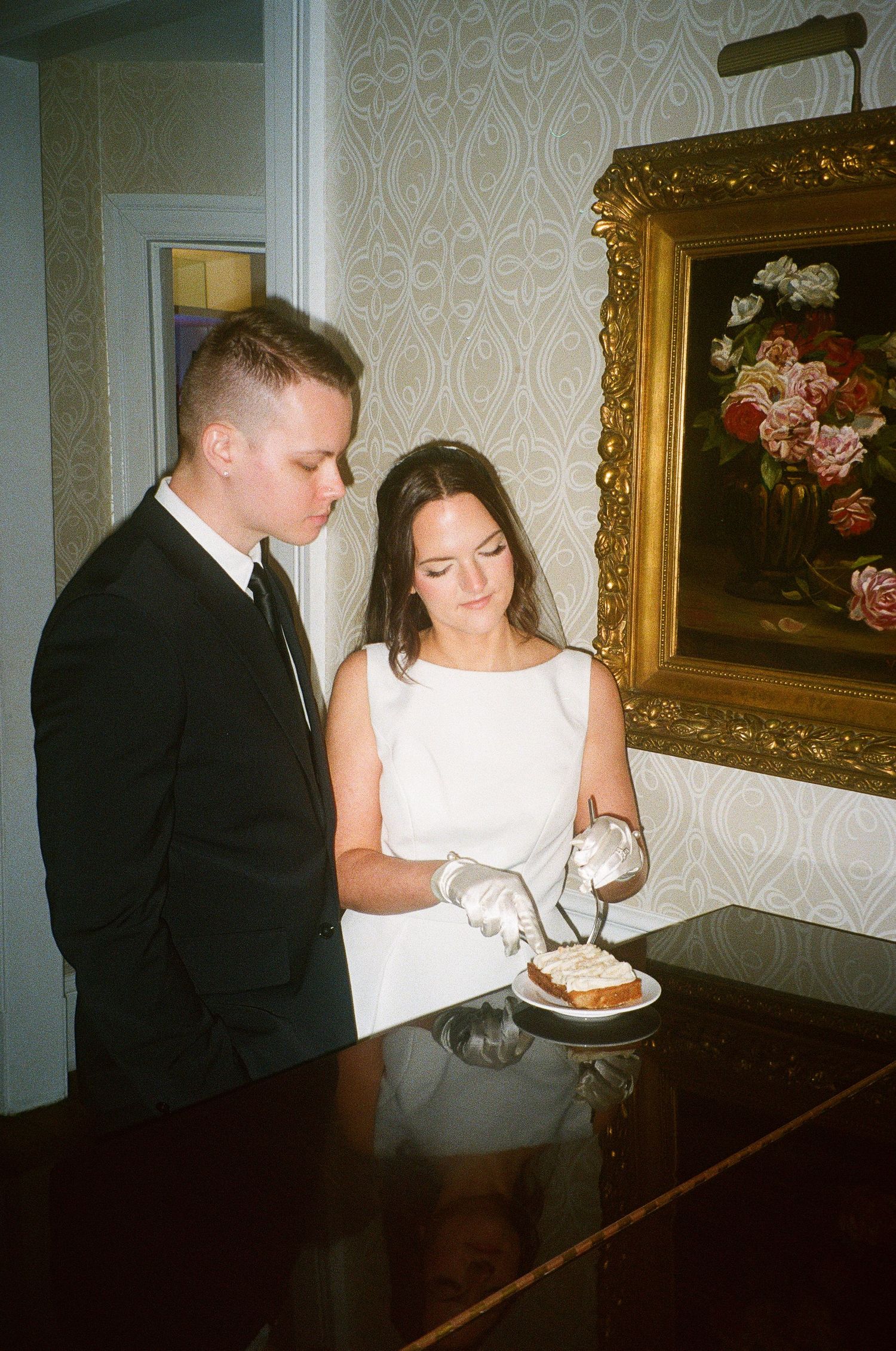 A couple in formal attire examines documents at a piano.