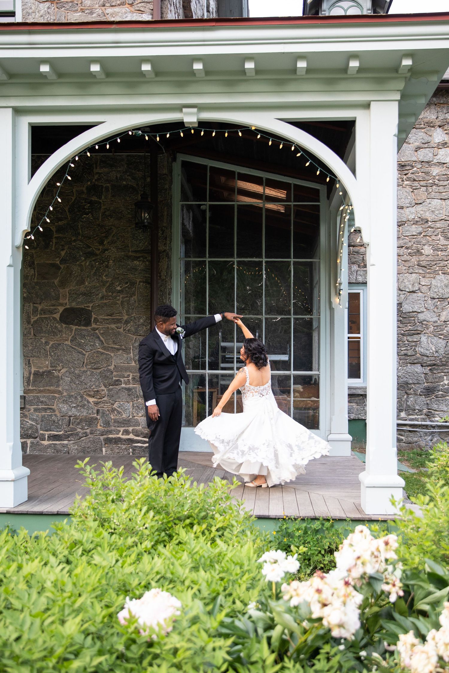 Wedding couple poses for romantic portraits on a stone building's covered porch.