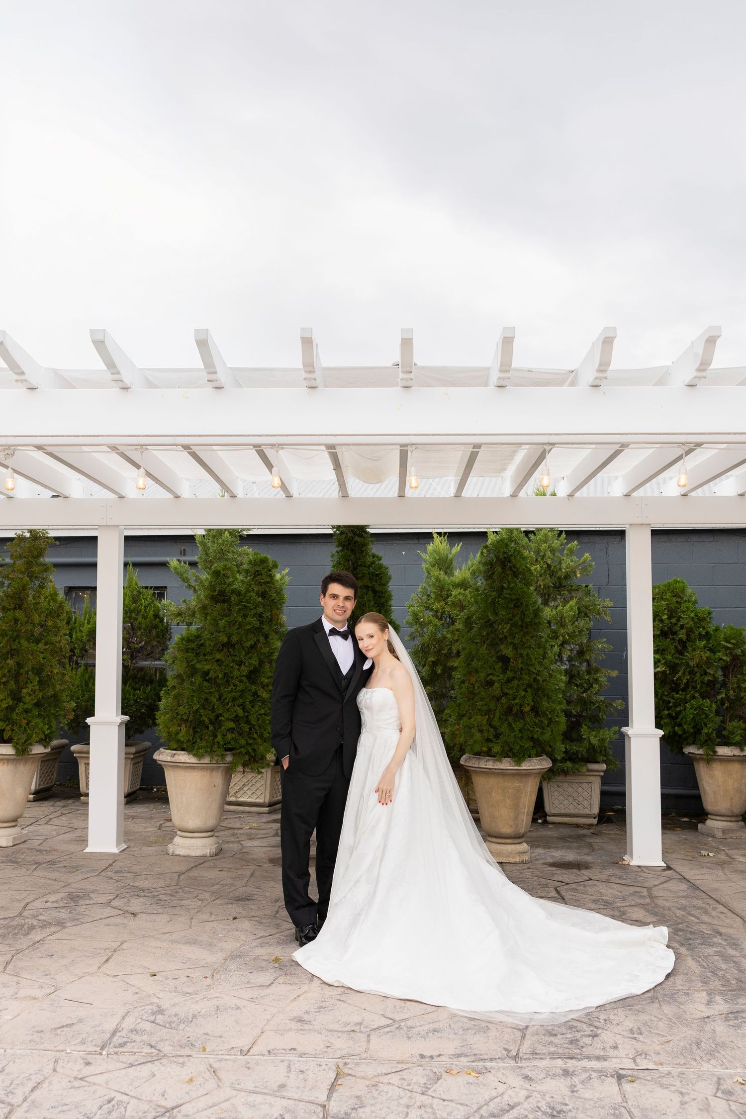 A romantic wedding portrait series under a white pergola with stone flooring.