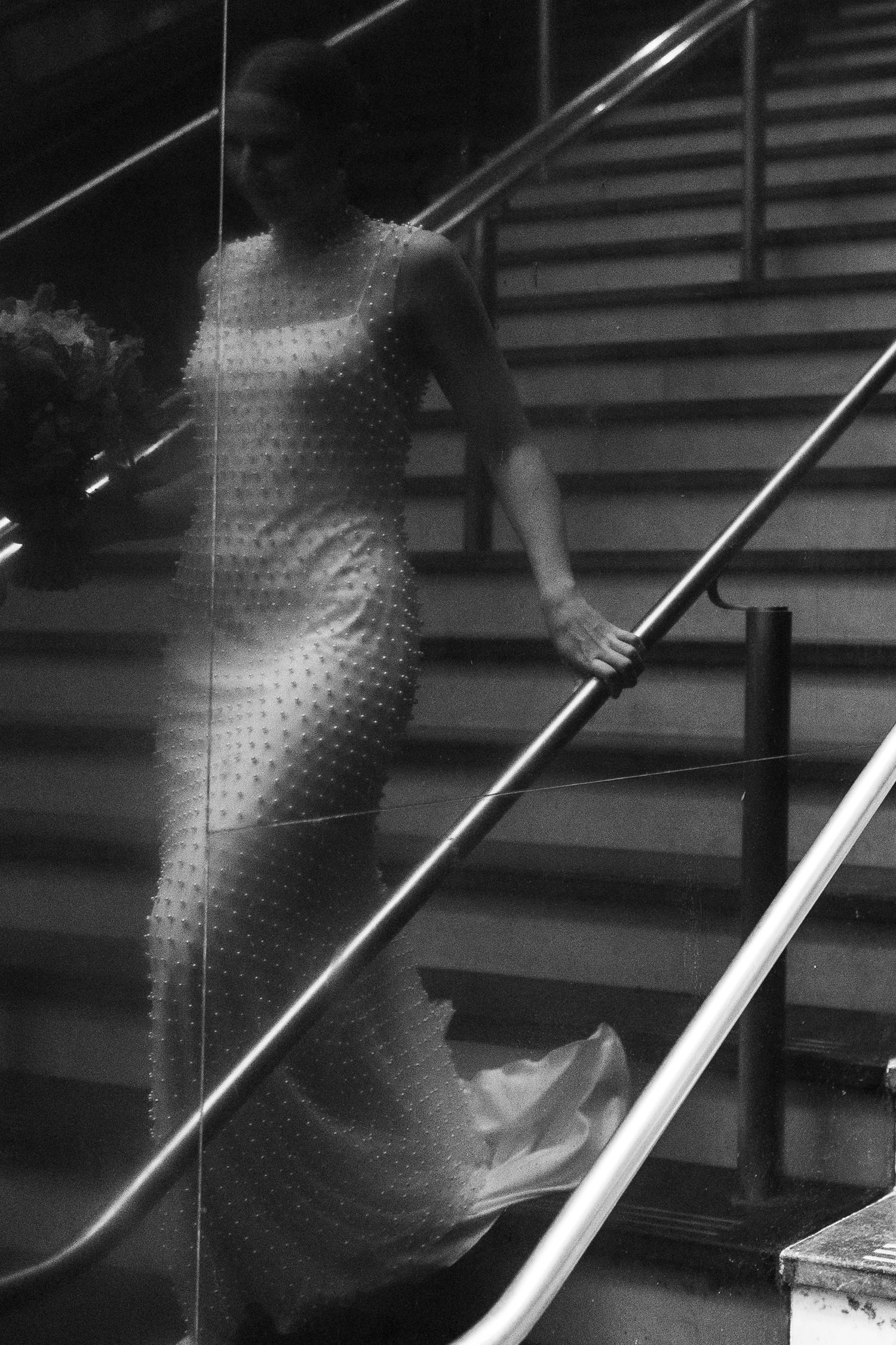 Artistic black and white photo of figure descending staircase in textured dress.