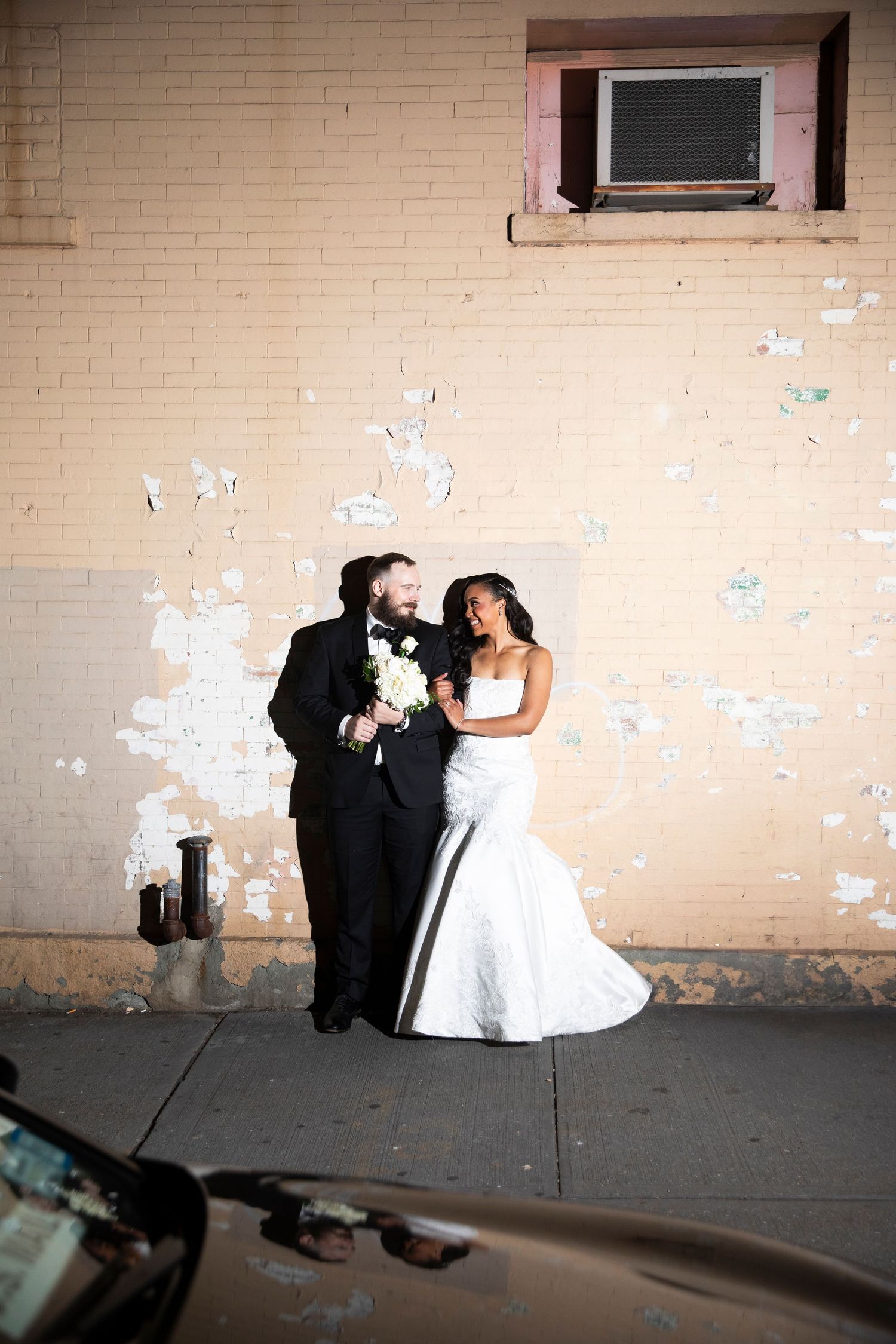Wedding photo against beige wall with artistic lighting and shadows.