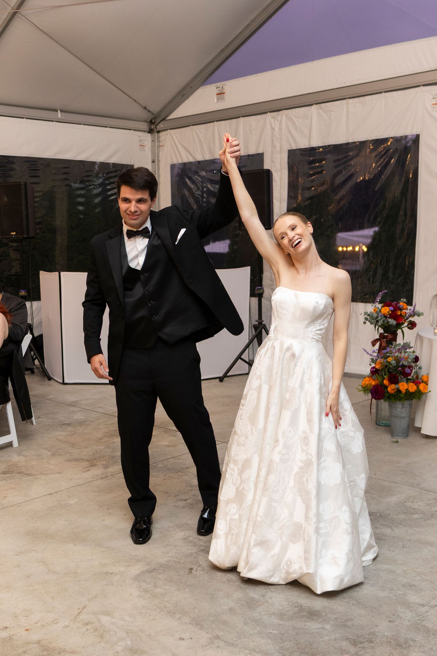 Newlyweds performing a choreographed dance routine in a white tent reception space.