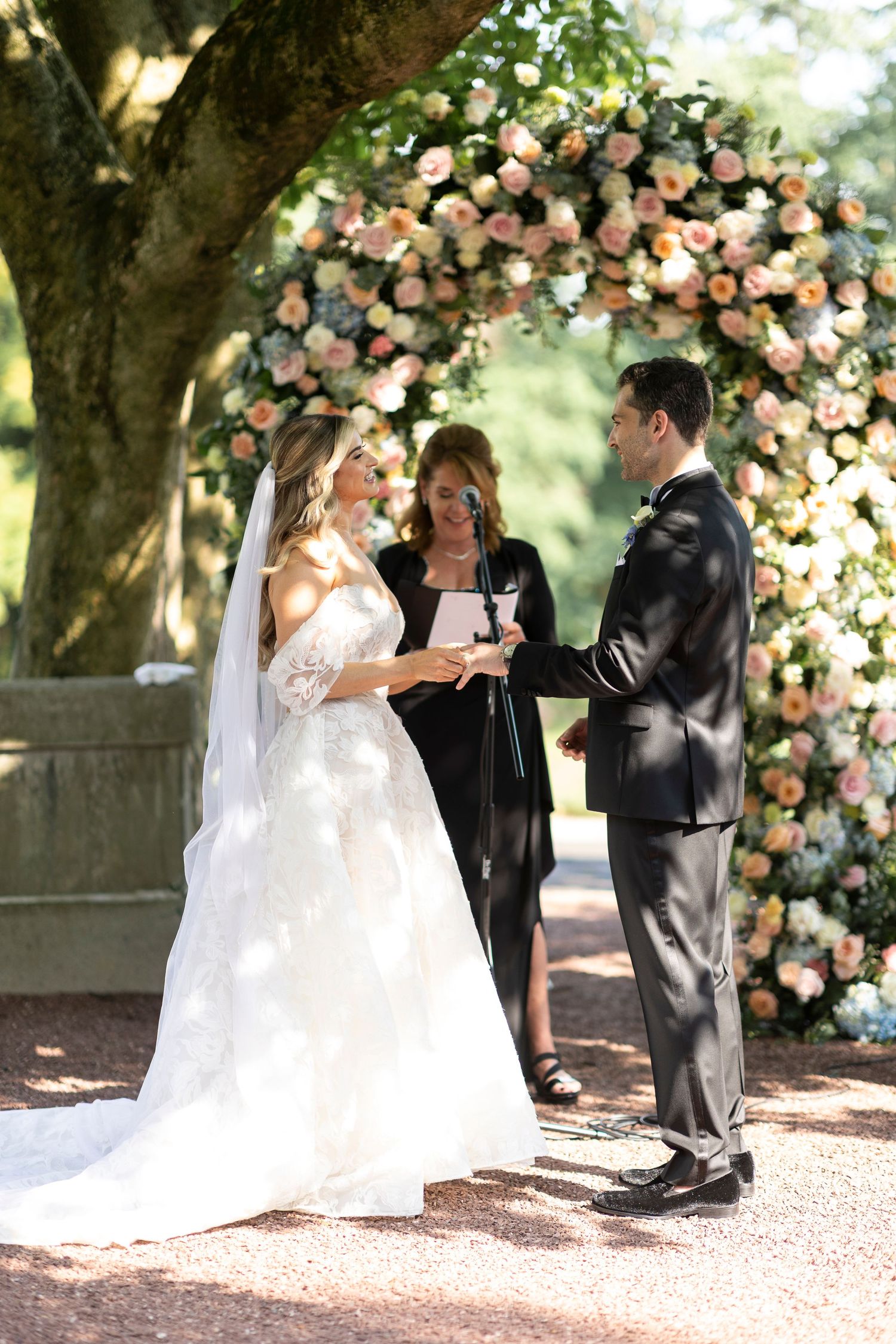 Intimate wedding ceremony moment under a lush floral arch in a garden setting.