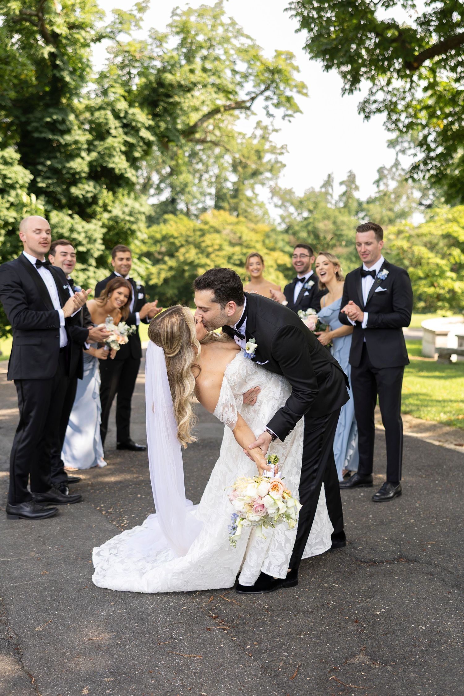 Wedding party having fun and dancing on outdoor path during photo session.