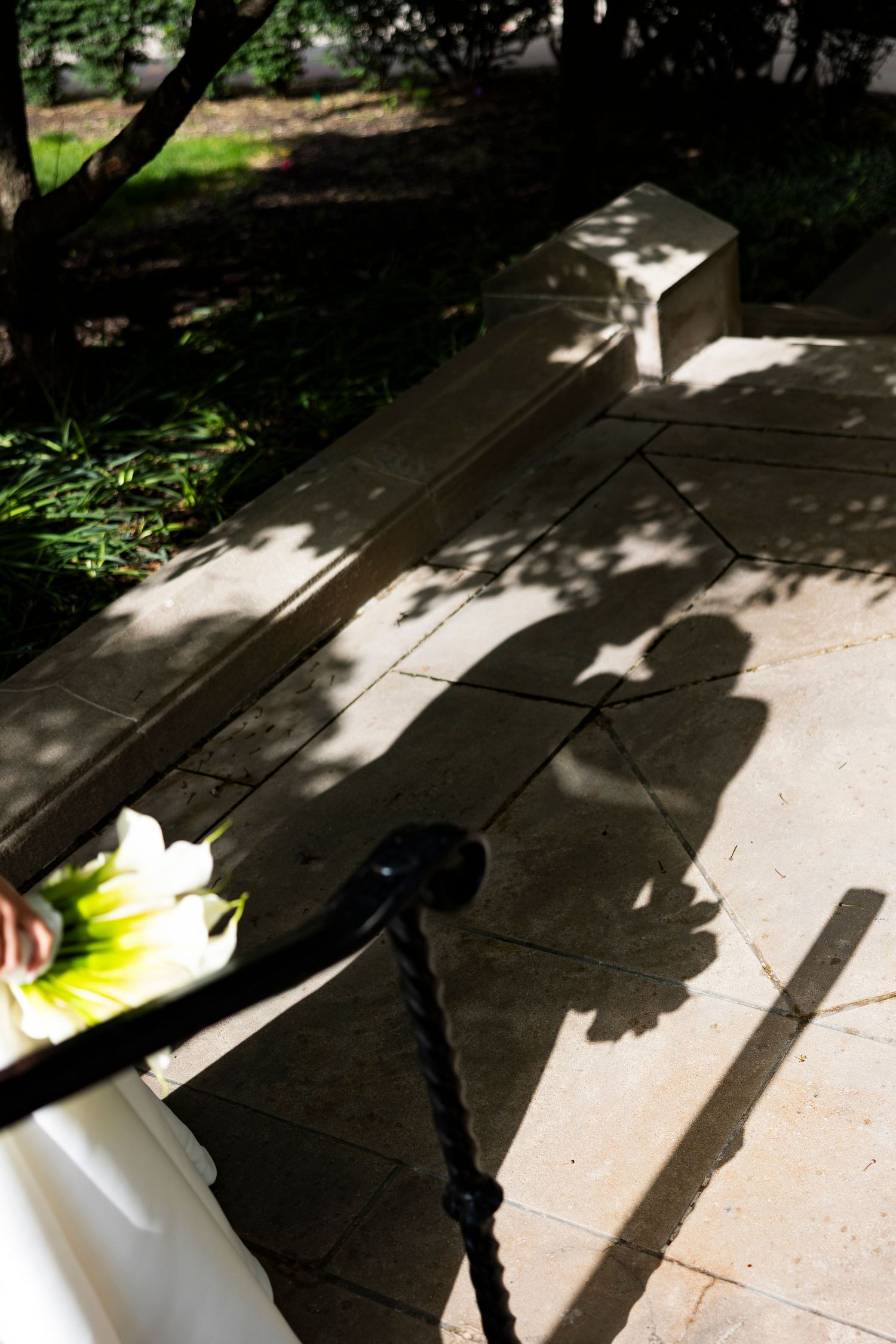 Creative shadow photography of a couple on stone pavement with flowers in the foreground.