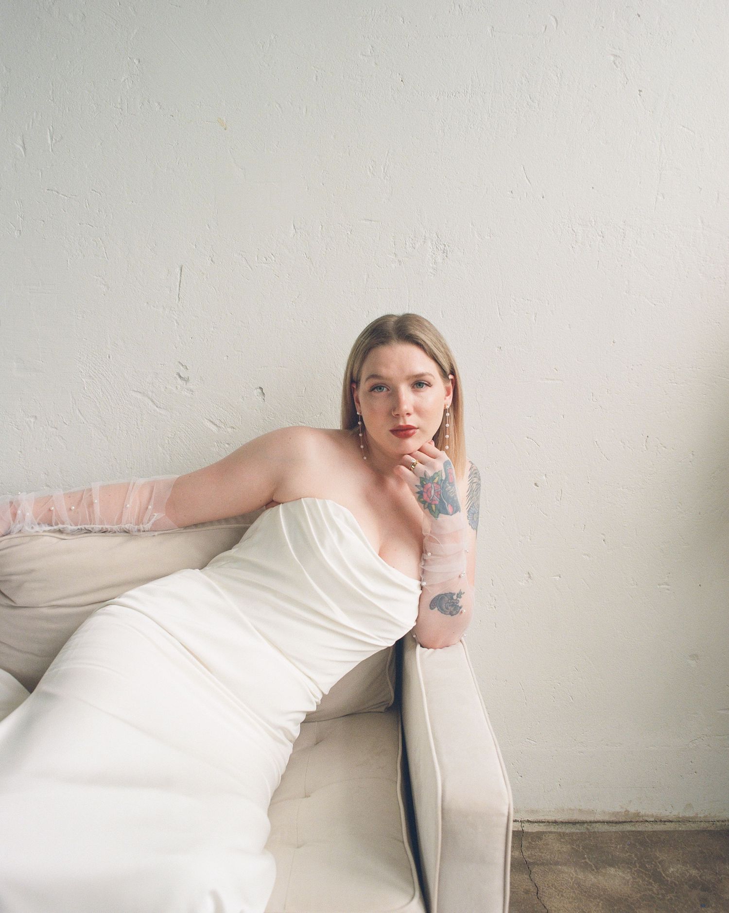 Artistic portrait series in white showing person lounging on modern sofa.