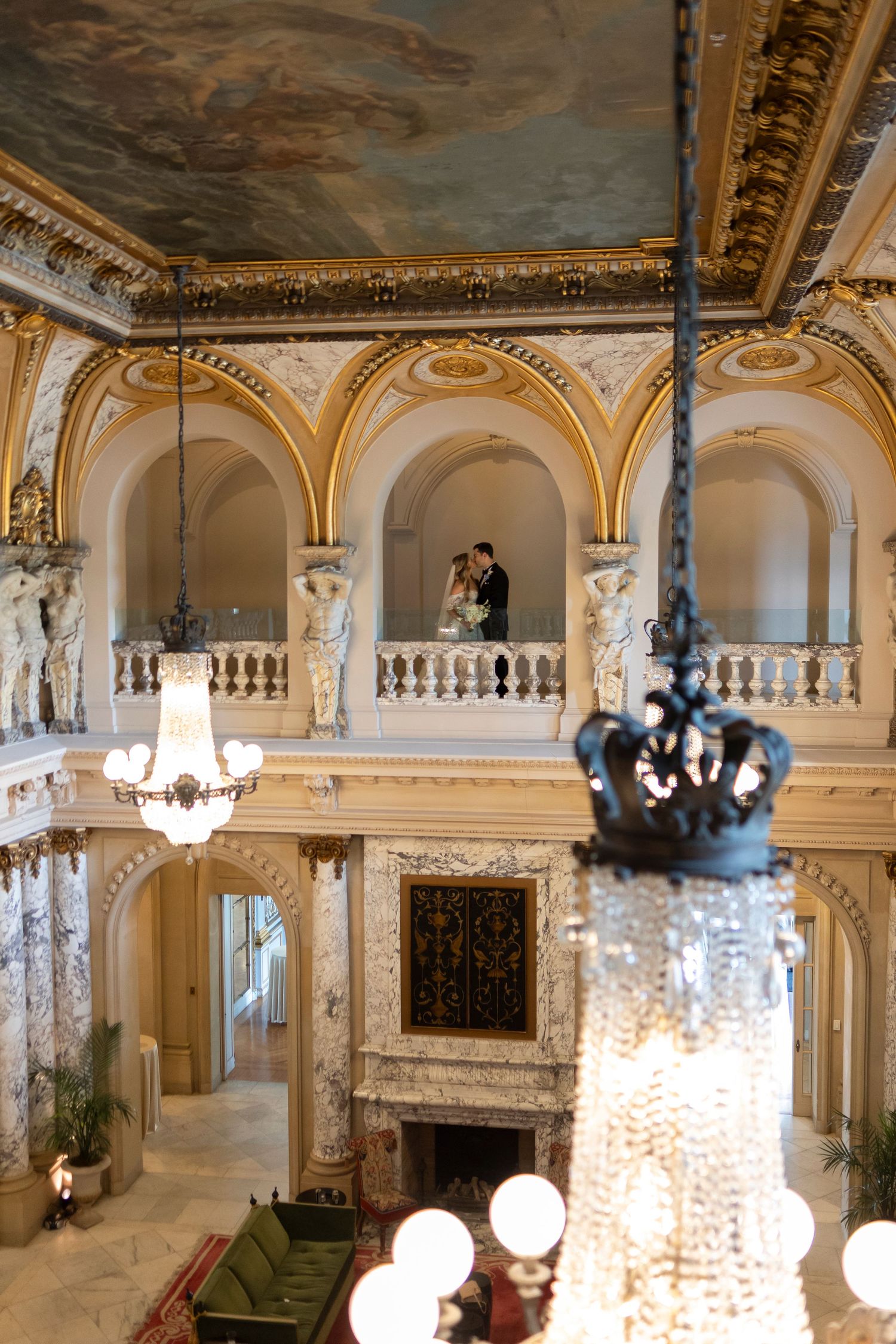 Grand ballroom interior with crystal chandeliers and gilded architectural details in warm lighting.