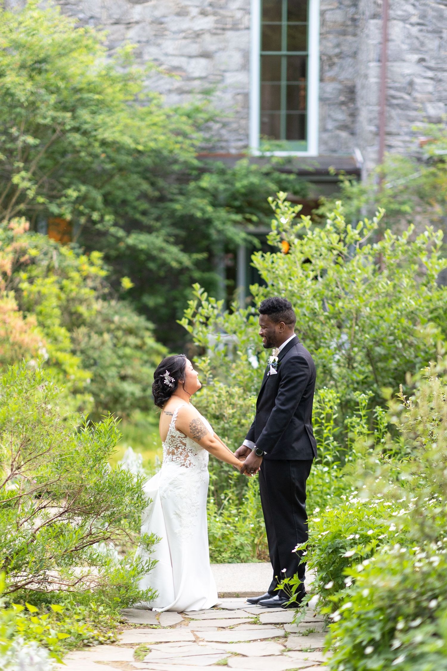 Wedding couple shares intimate moments in a lush garden with stone wall backdrop.
