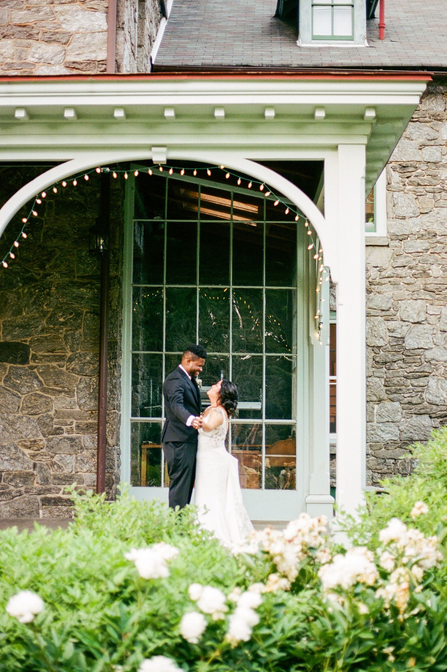 Elegant wedding couple photographed against a stone building with white columns.