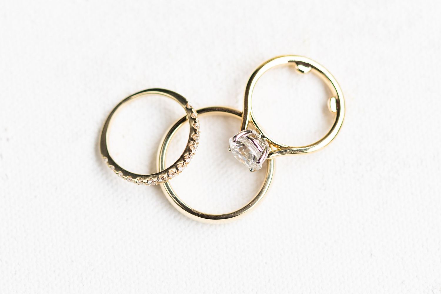 Three gold wedding rings artistically arranged on a white background.