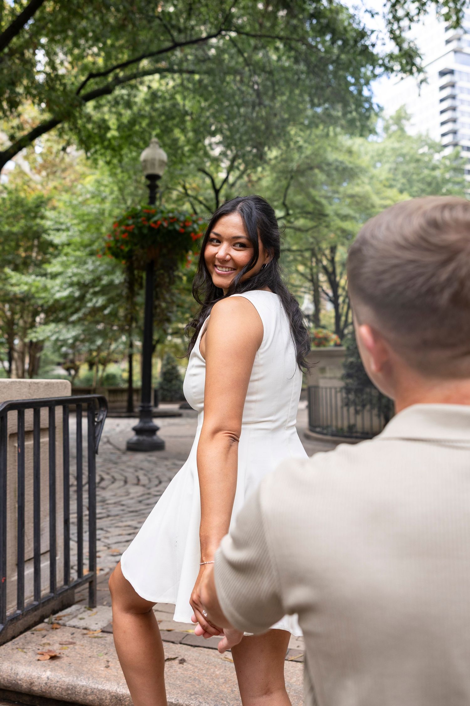 Playful outdoor photoshoot sequence with a couple on a brick pathway surrounded by trees.