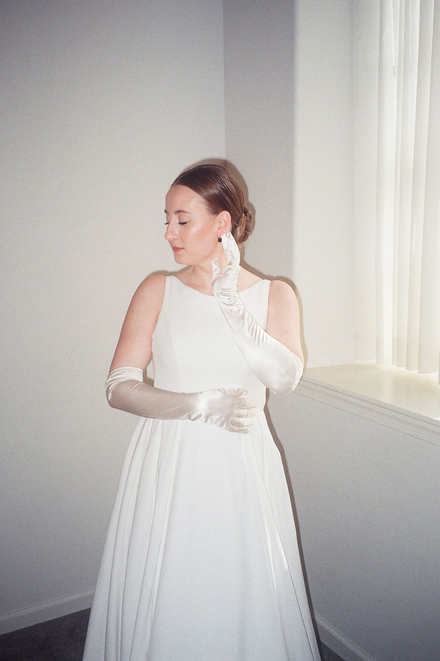 Ethereal bridal portraits in white dress against minimalist grey background.