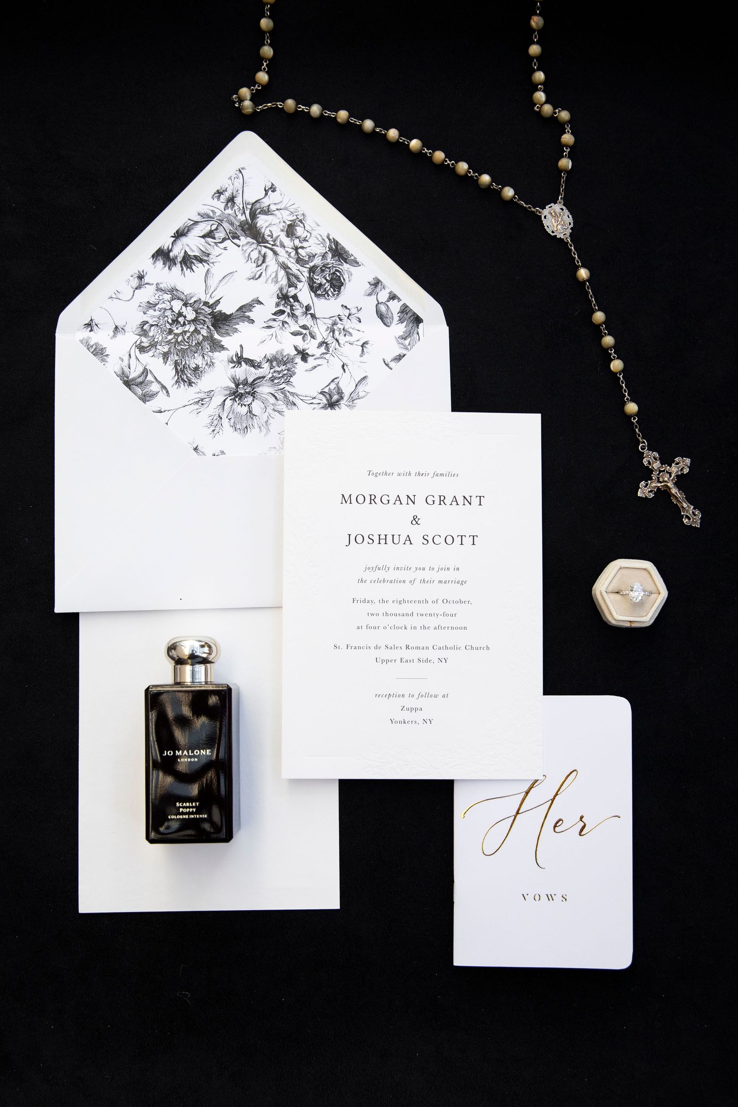 Elegant wedding invitation suite with floral details and gold jewelry accents on black background.