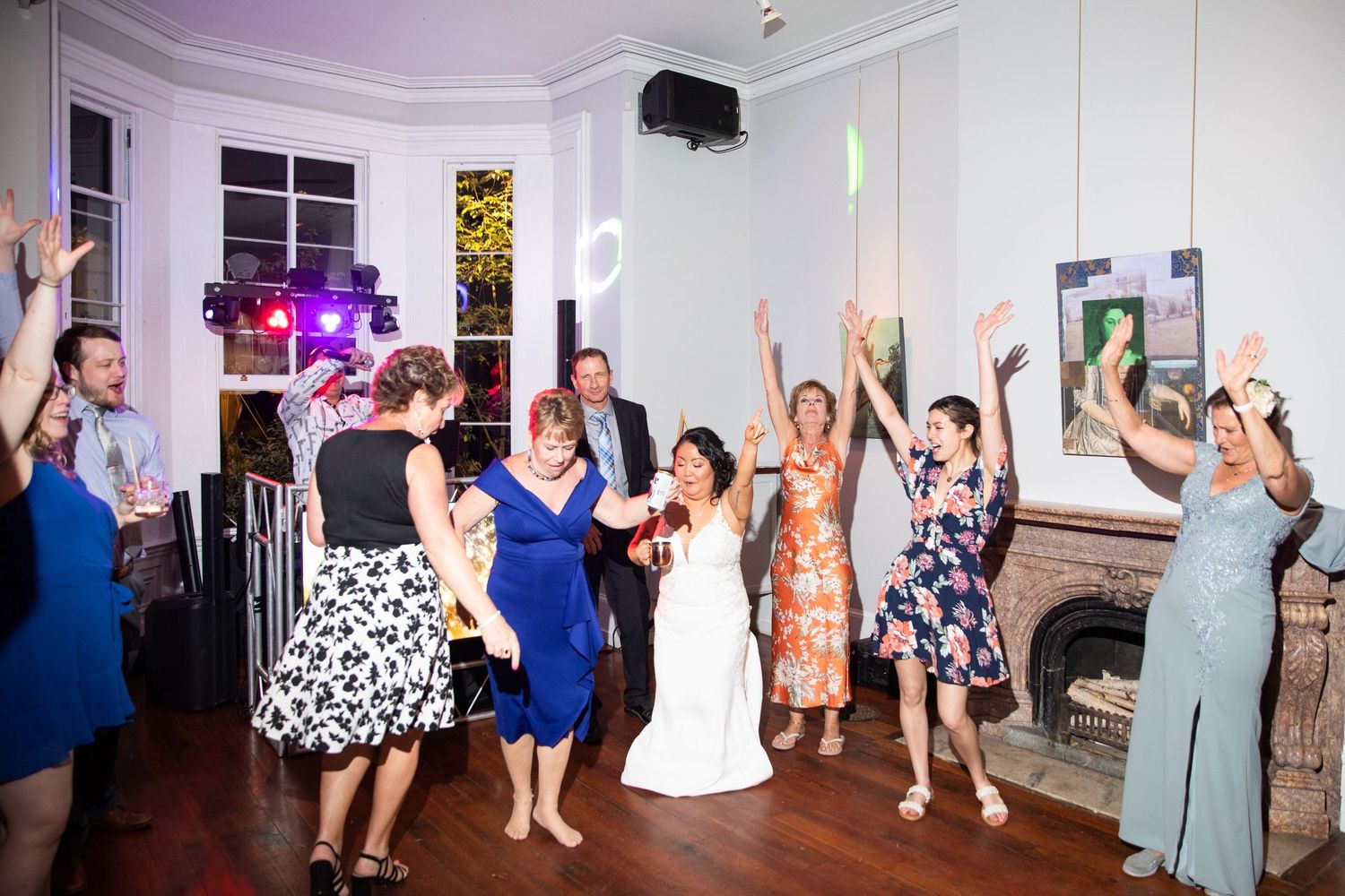 Energetic wedding reception with guests dancing under purple lighting.