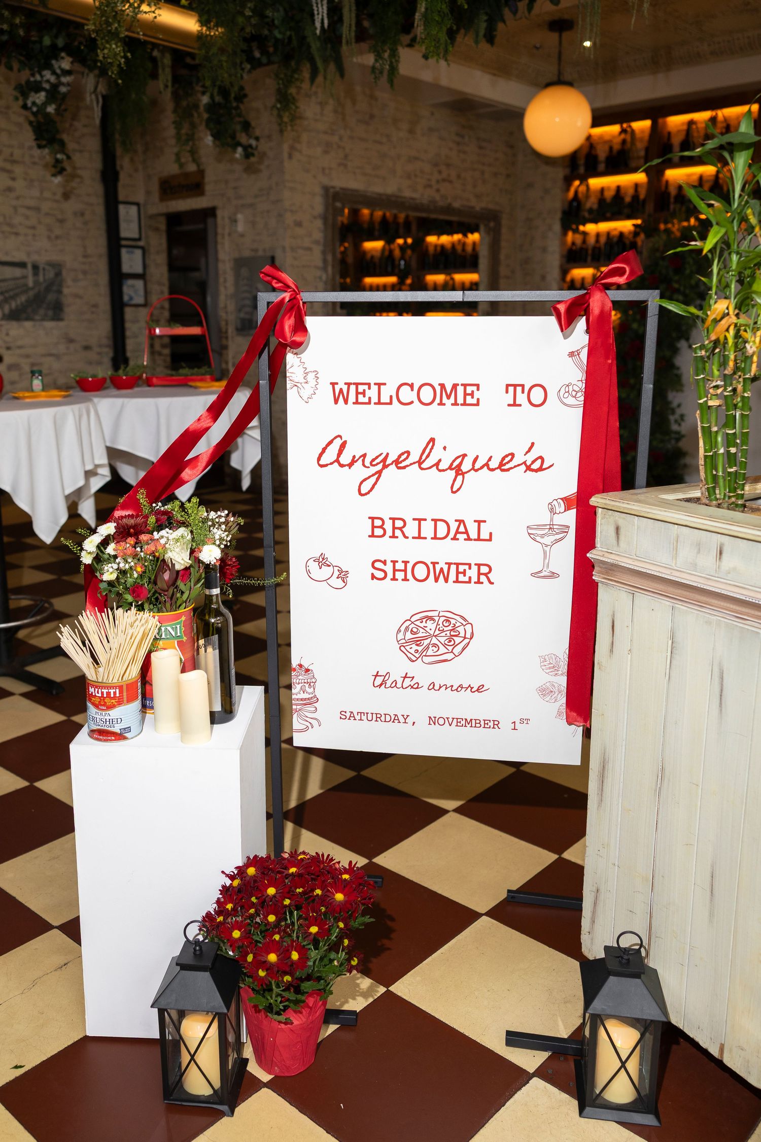 Red and white bridal shower welcome signs displayed with lanterns and flowers.
