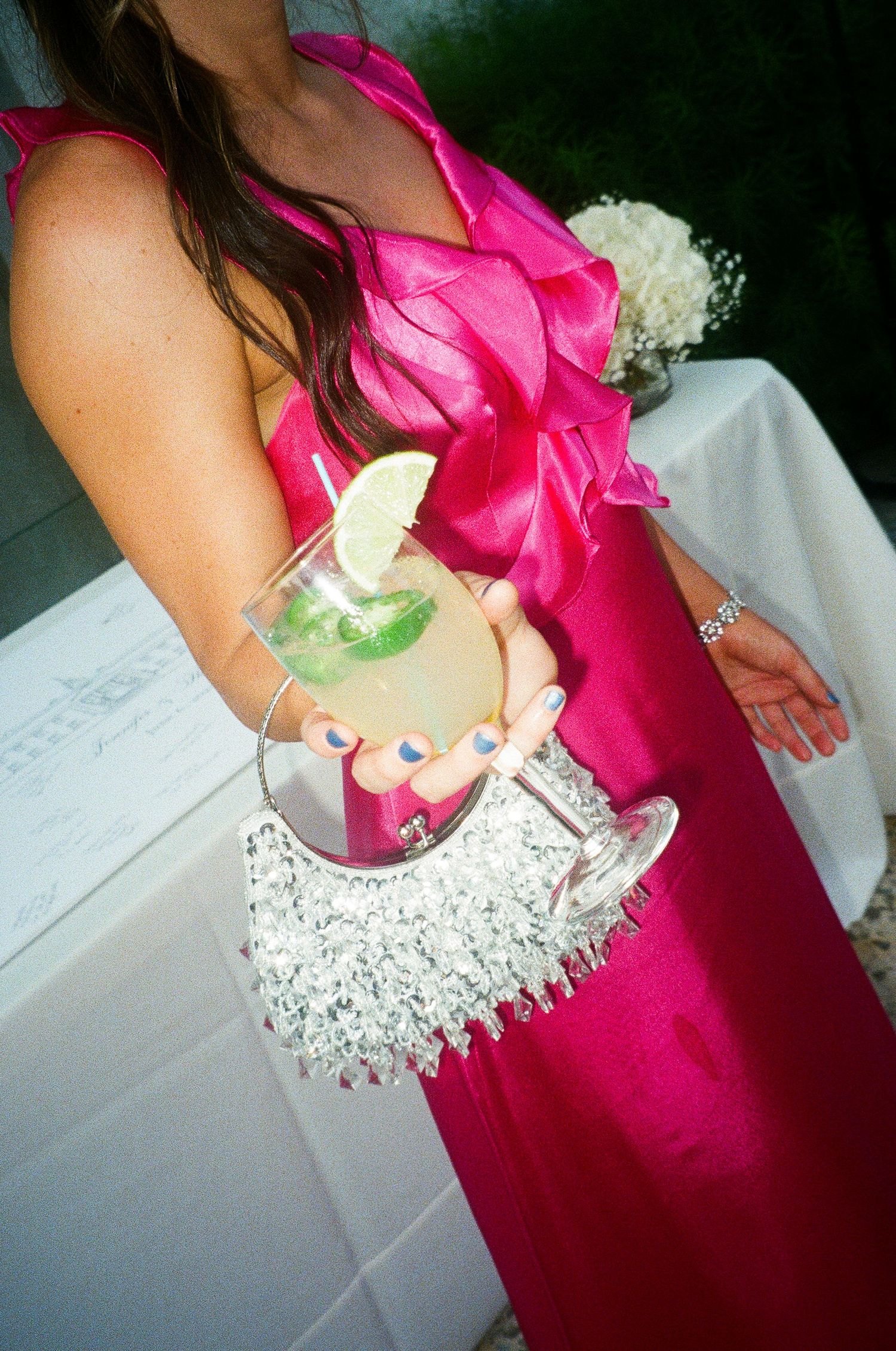 Close-up detail of bright pink bridesmaid dress with white corsage and sparkly neckline.