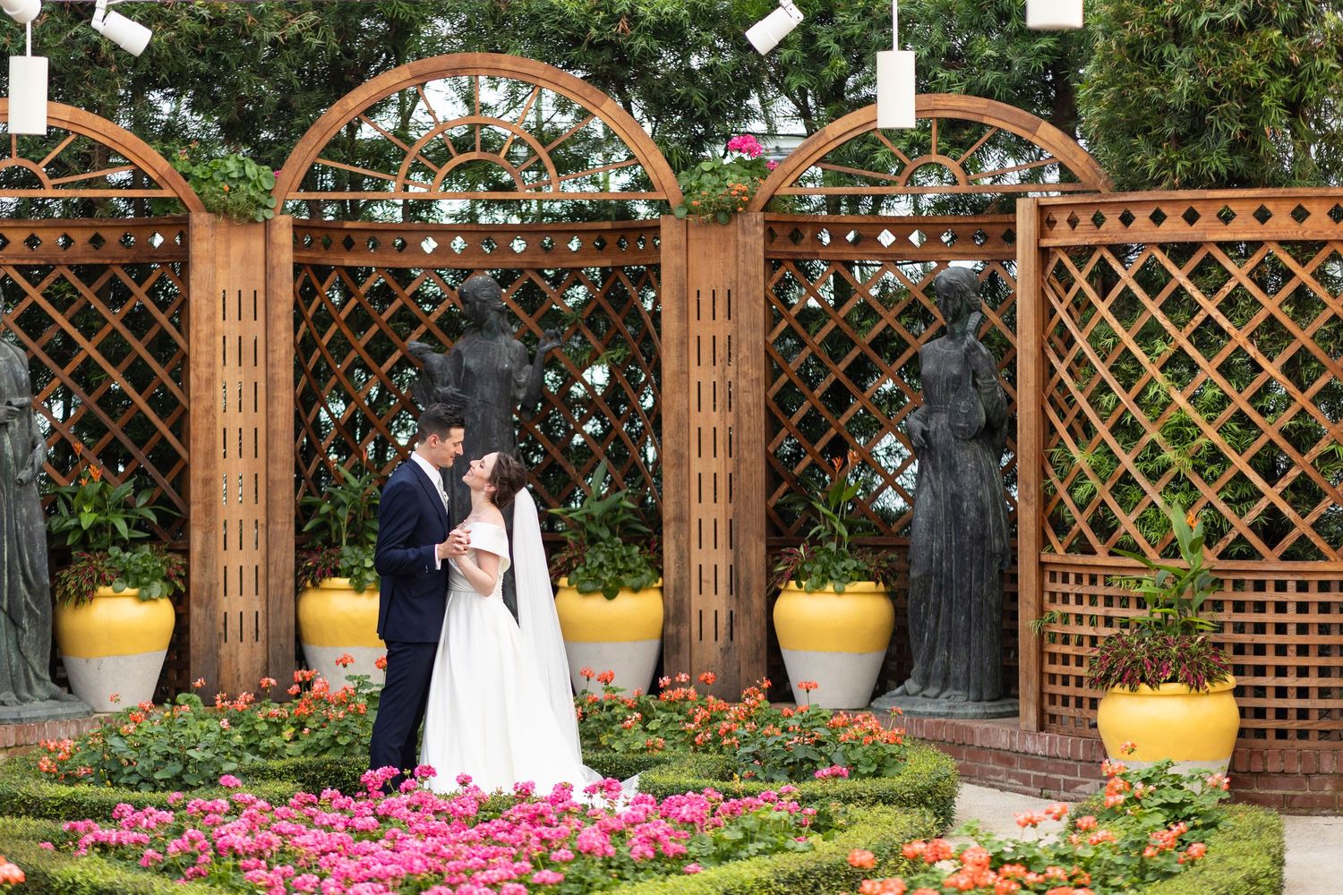 Wedding ceremony under wooden pergola decorated with string lights and floral arrangements.