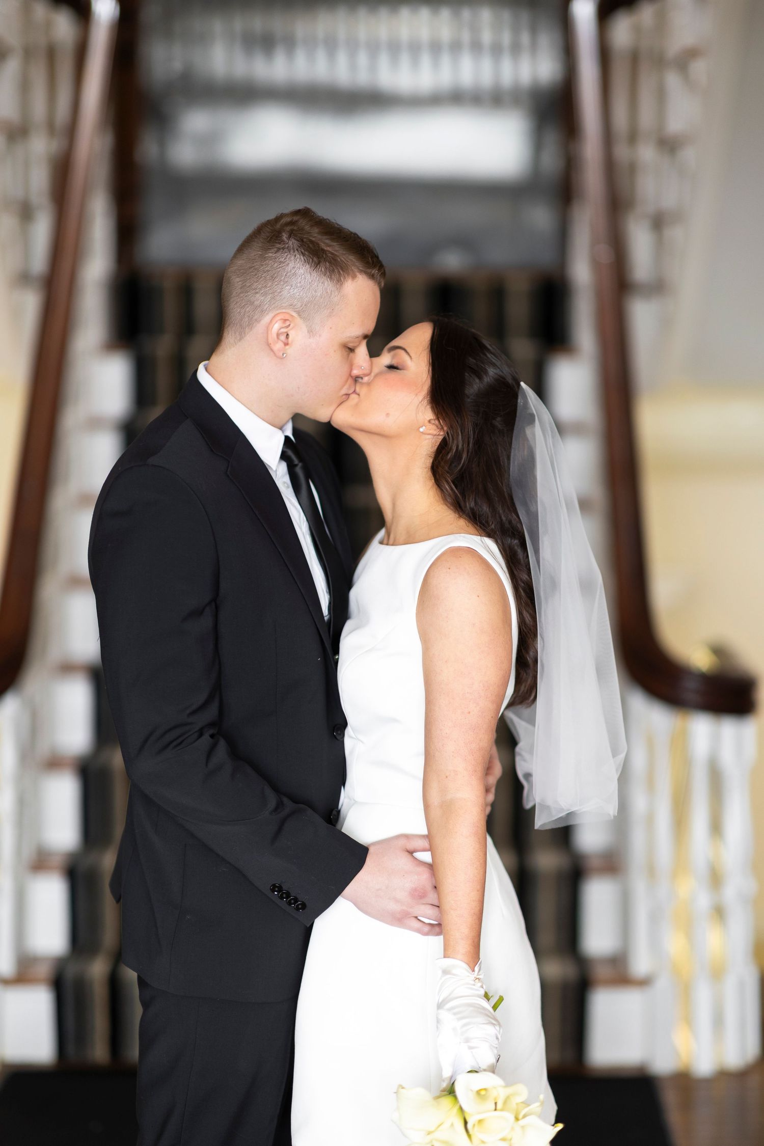 A tender wedding moment captured as a couple shares a kiss in formal attire.