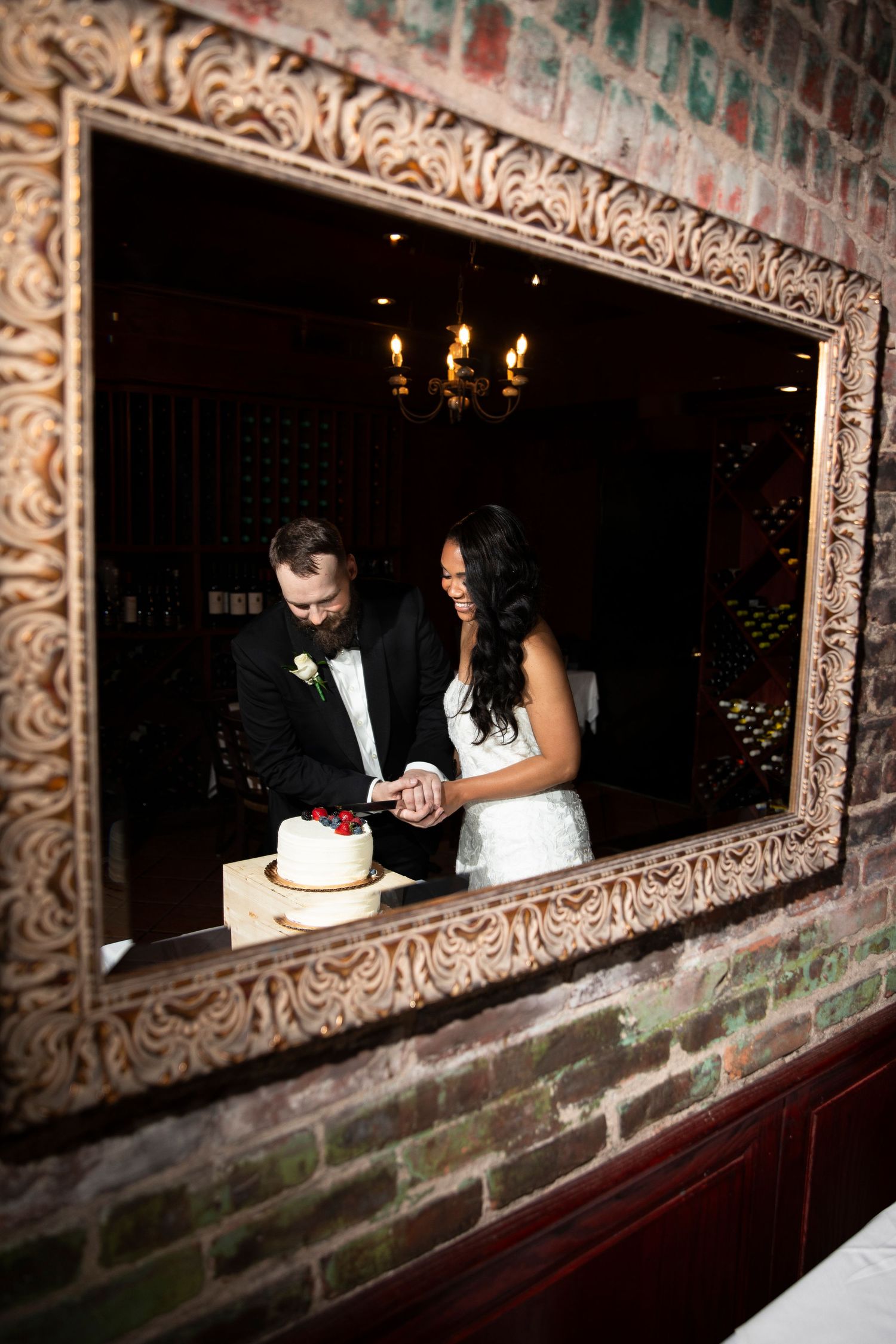 Wedding couple reflected in an ornate mirror during their reception.