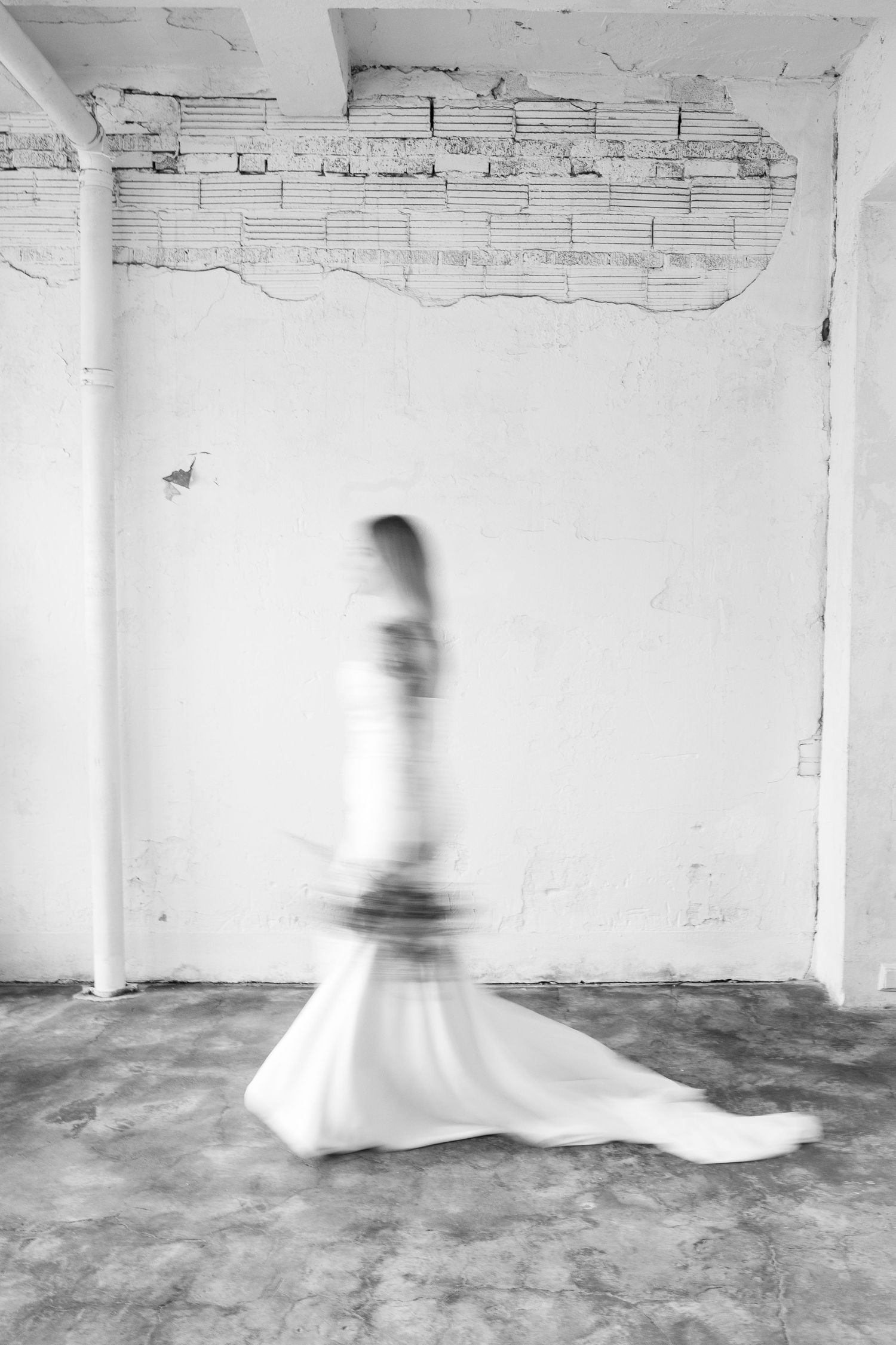 Motion blur artistic series of figure in white dress against industrial backdrop.