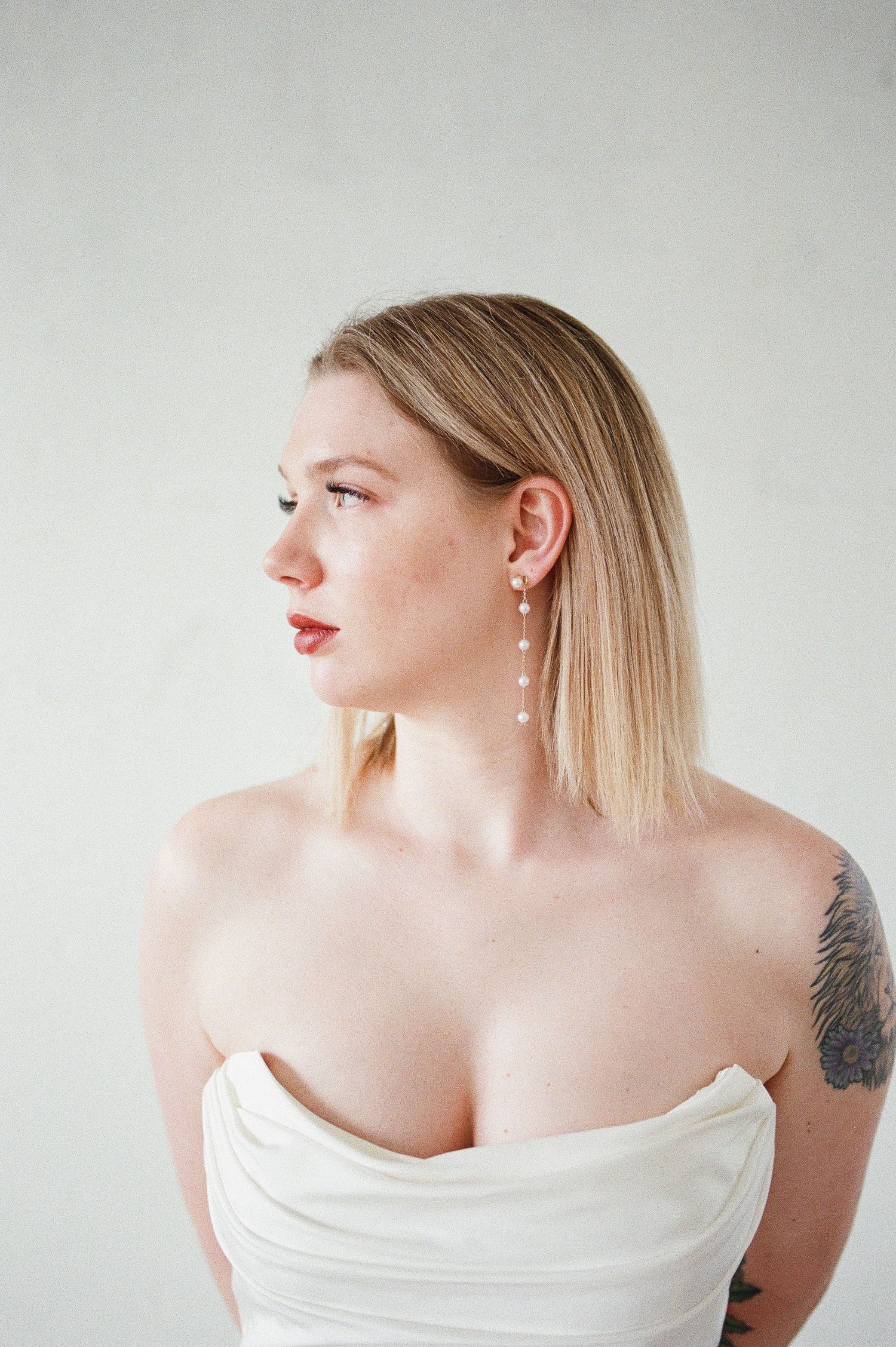 Artistic portrait series showing an off-shoulder white dress against a light background with delicate details.