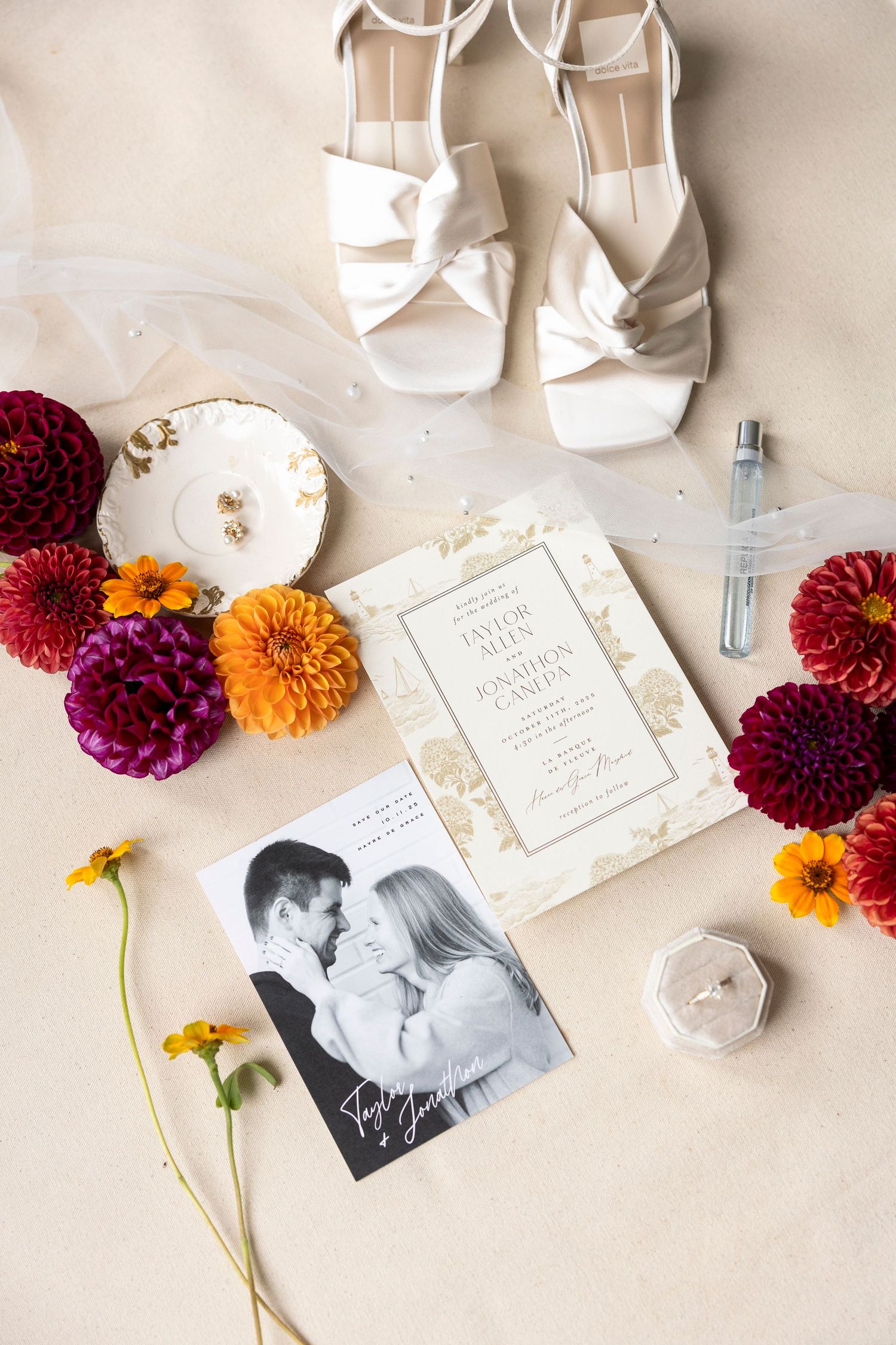 Wedding details flatlay with invitation, white shoes, and vibrant autumn flowers.