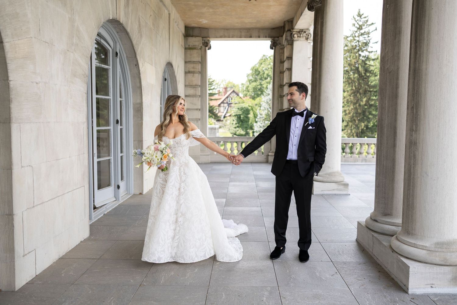 Wedding couple poses in a dramatic architectural corridor with columns.
