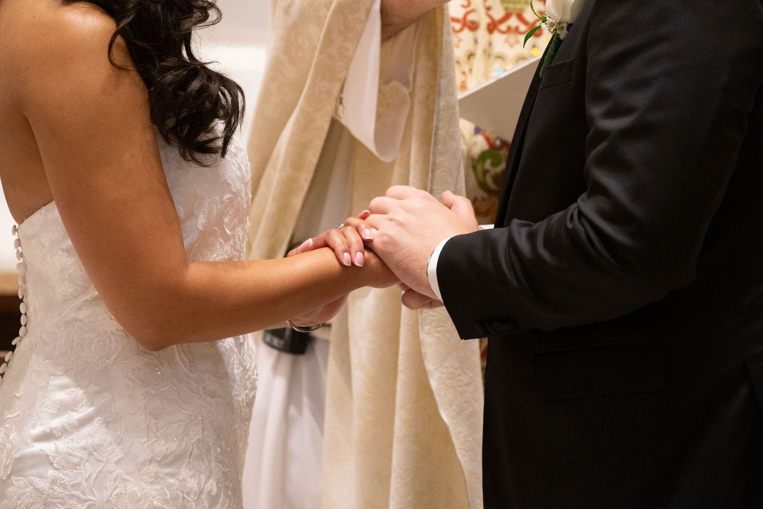 Close-up of wedding ceremony details showing hands exchanging rings at the altar.