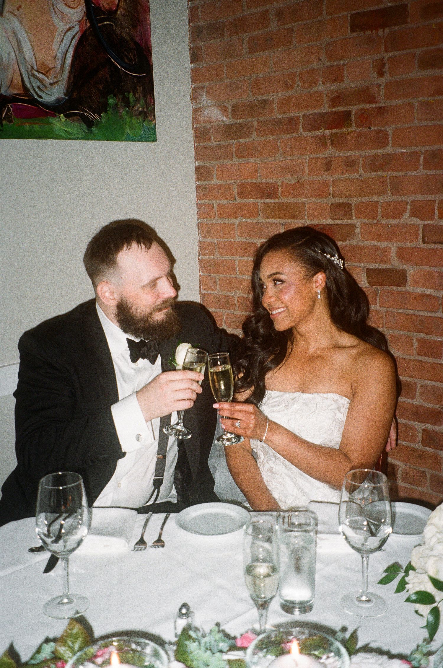 Wedding reception table setup with exposed brick wall and elegant place settings.