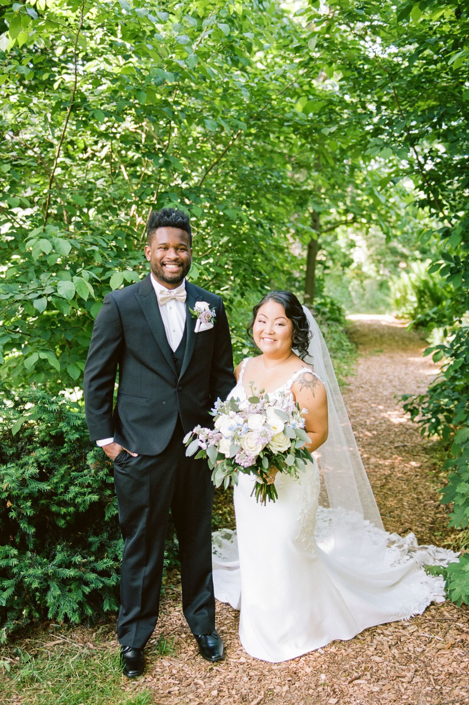 Wedding couple sharing joyful moments in a wooded garden setting.