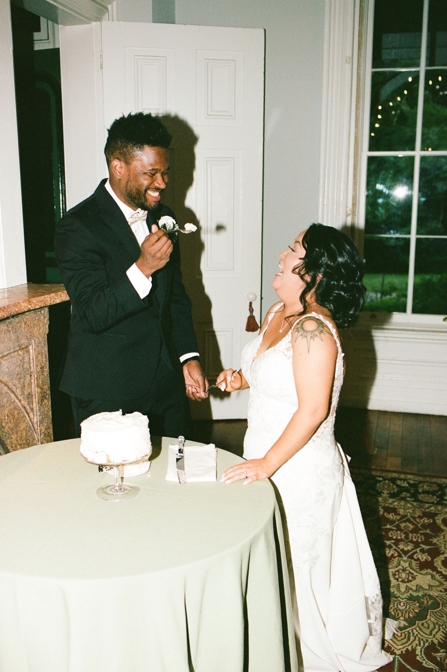 Joyful wedding reception scene with couple sharing playful moments at white-clothed table.