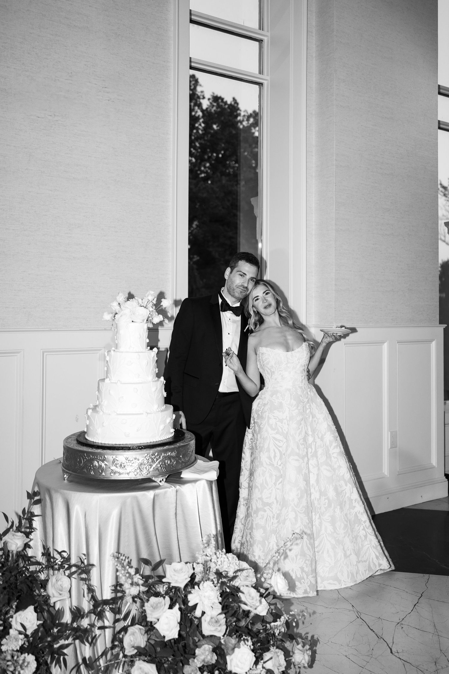 Wedding cake cutting moment captured in black and white photography.