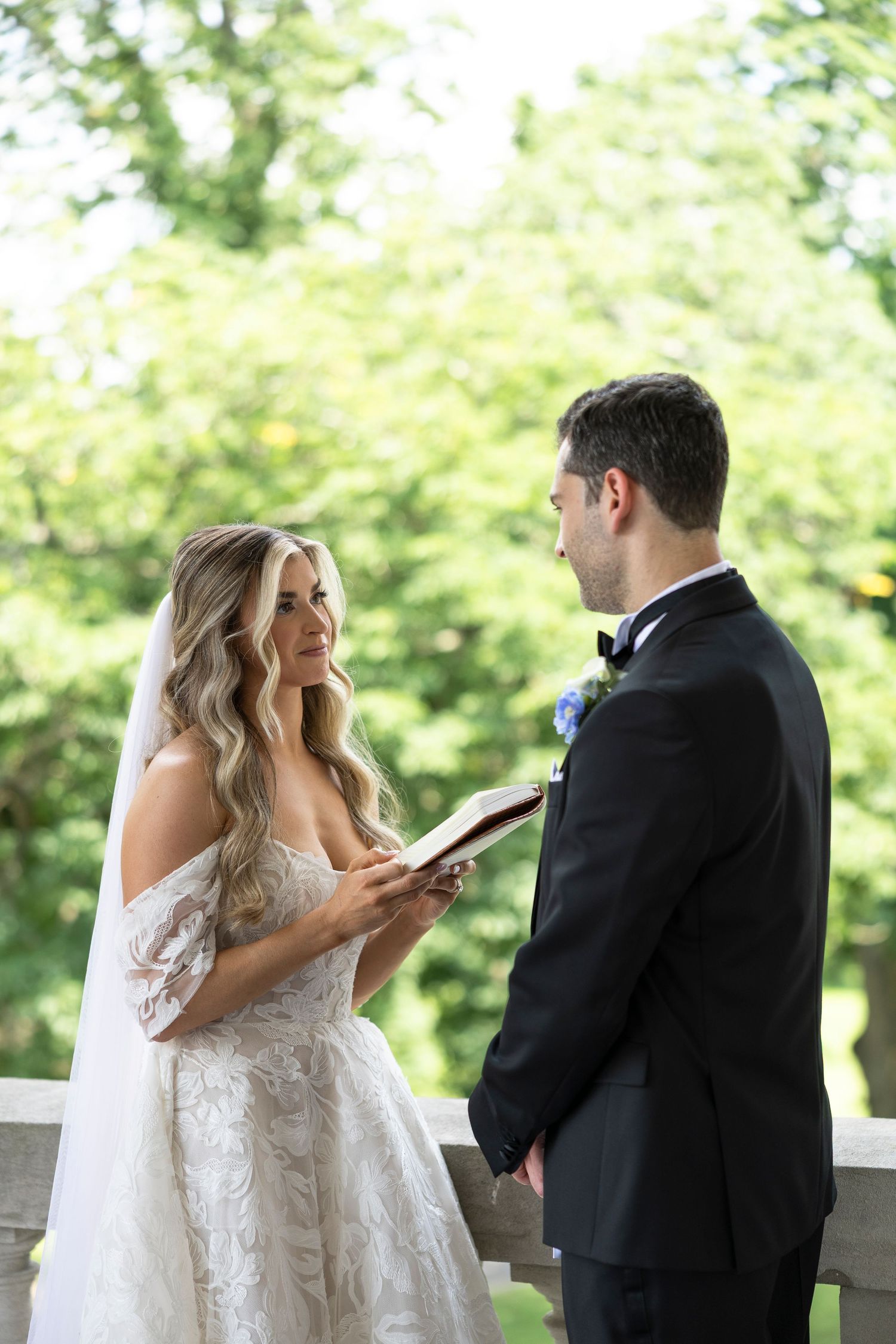 Bride and groom read personal vows to each other in an outdoor garden setting.