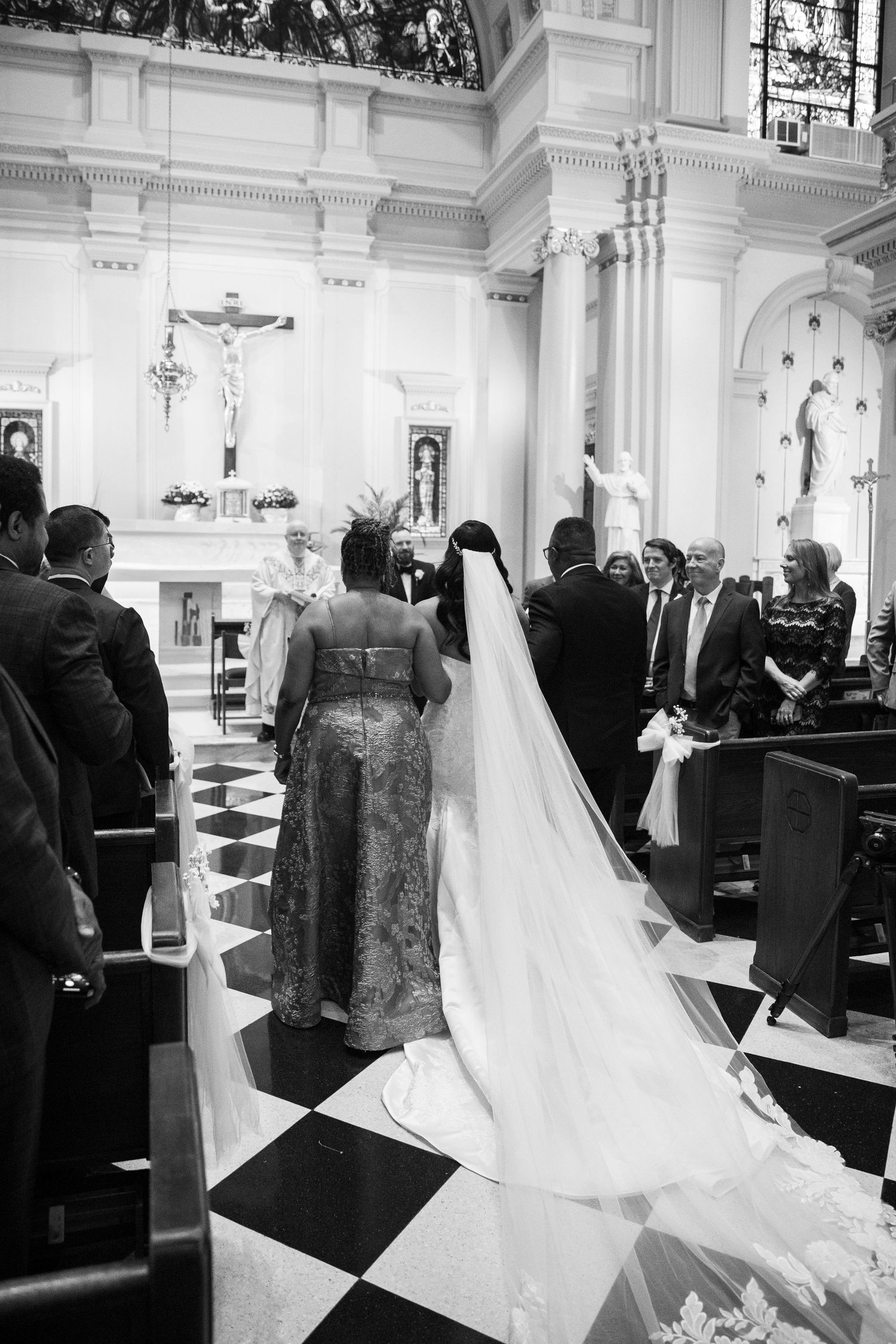 Wedding ceremony in progress inside a traditional church with white columns and decorative ceiling.