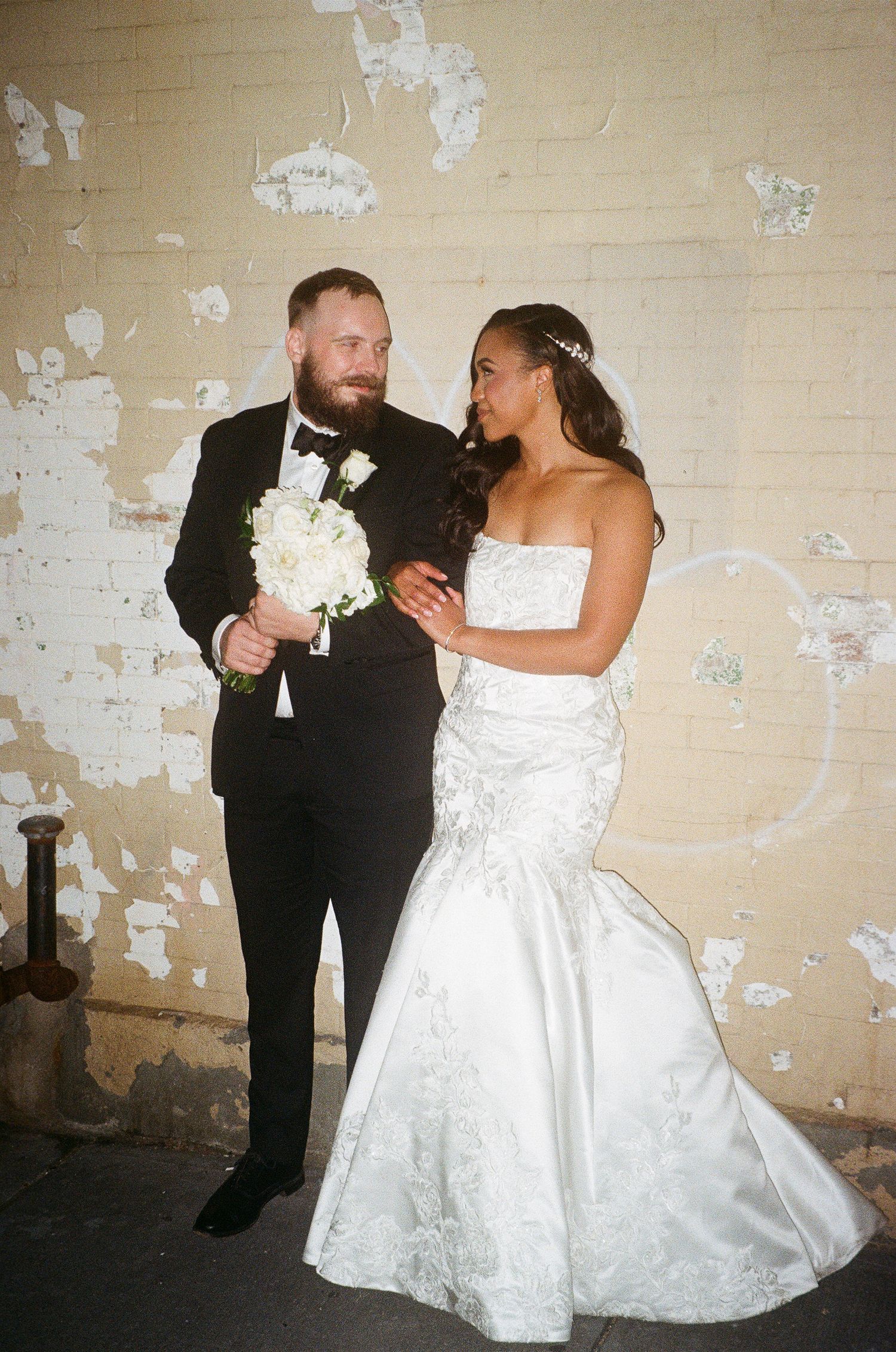 A couple shares a romantic dance moment against a distressed wall background.