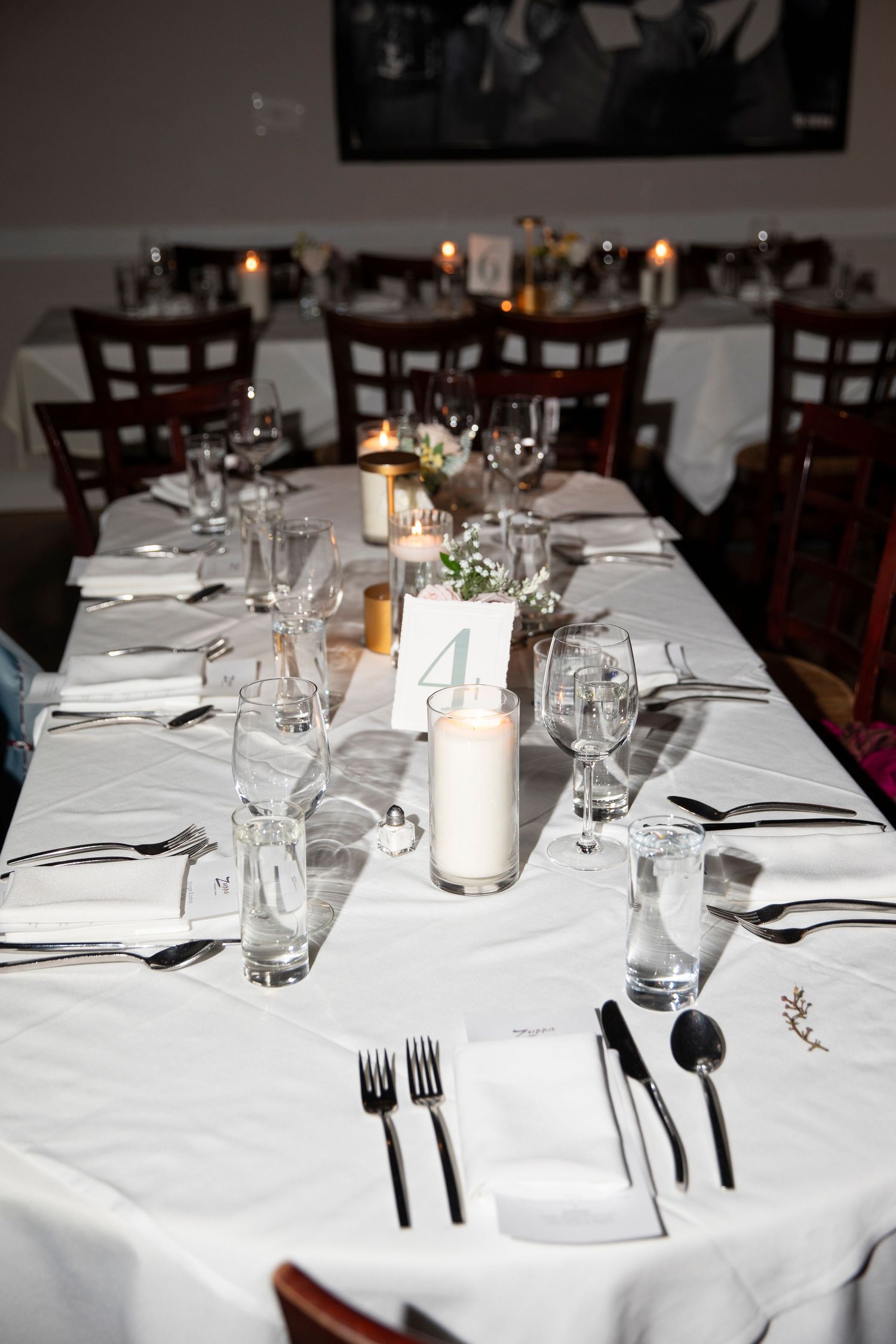 Formal dining table set with white linens, glassware, and elegant place settings.