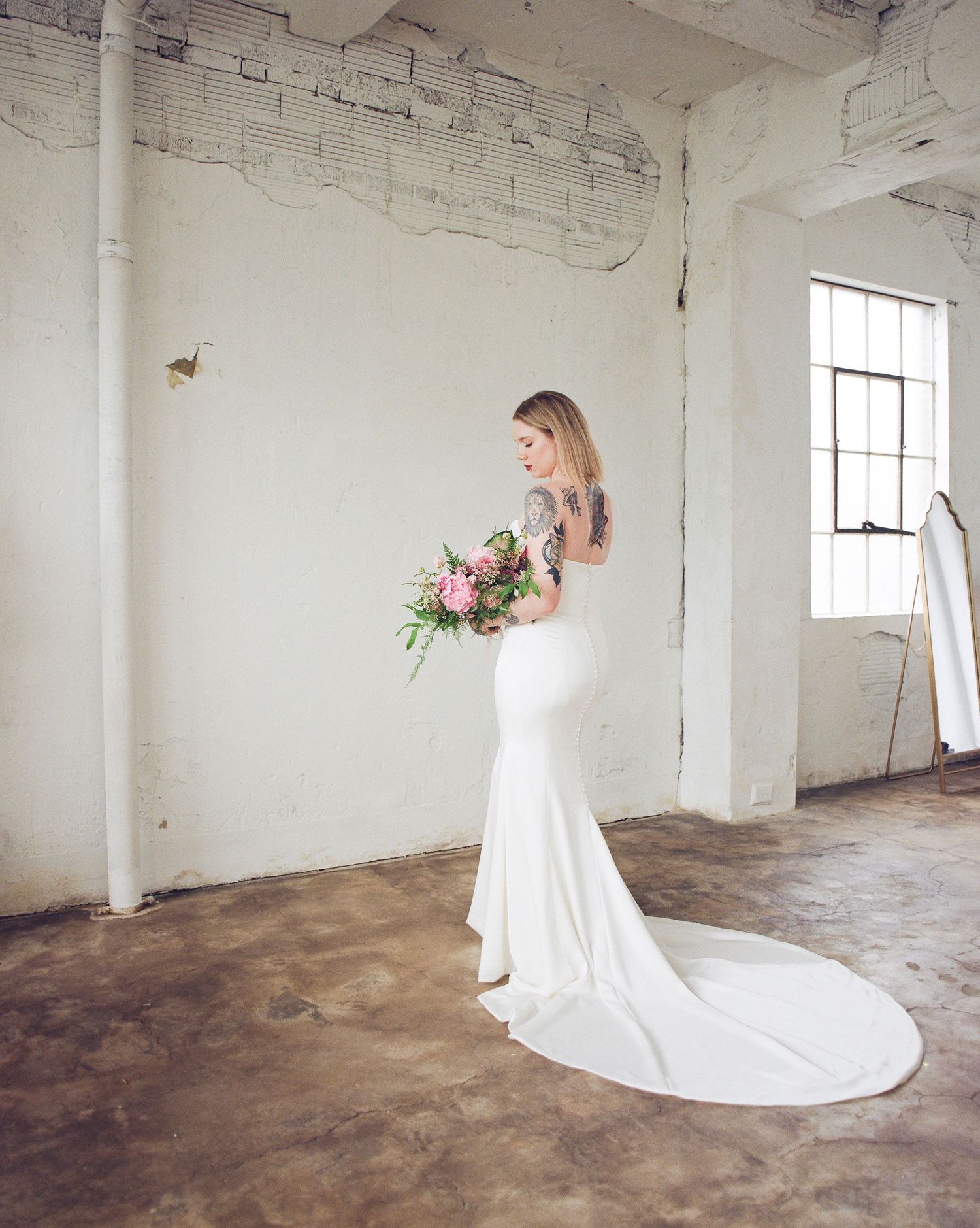 Elegant bridal portrait series in white gown against industrial white brick walls with dramatic train.