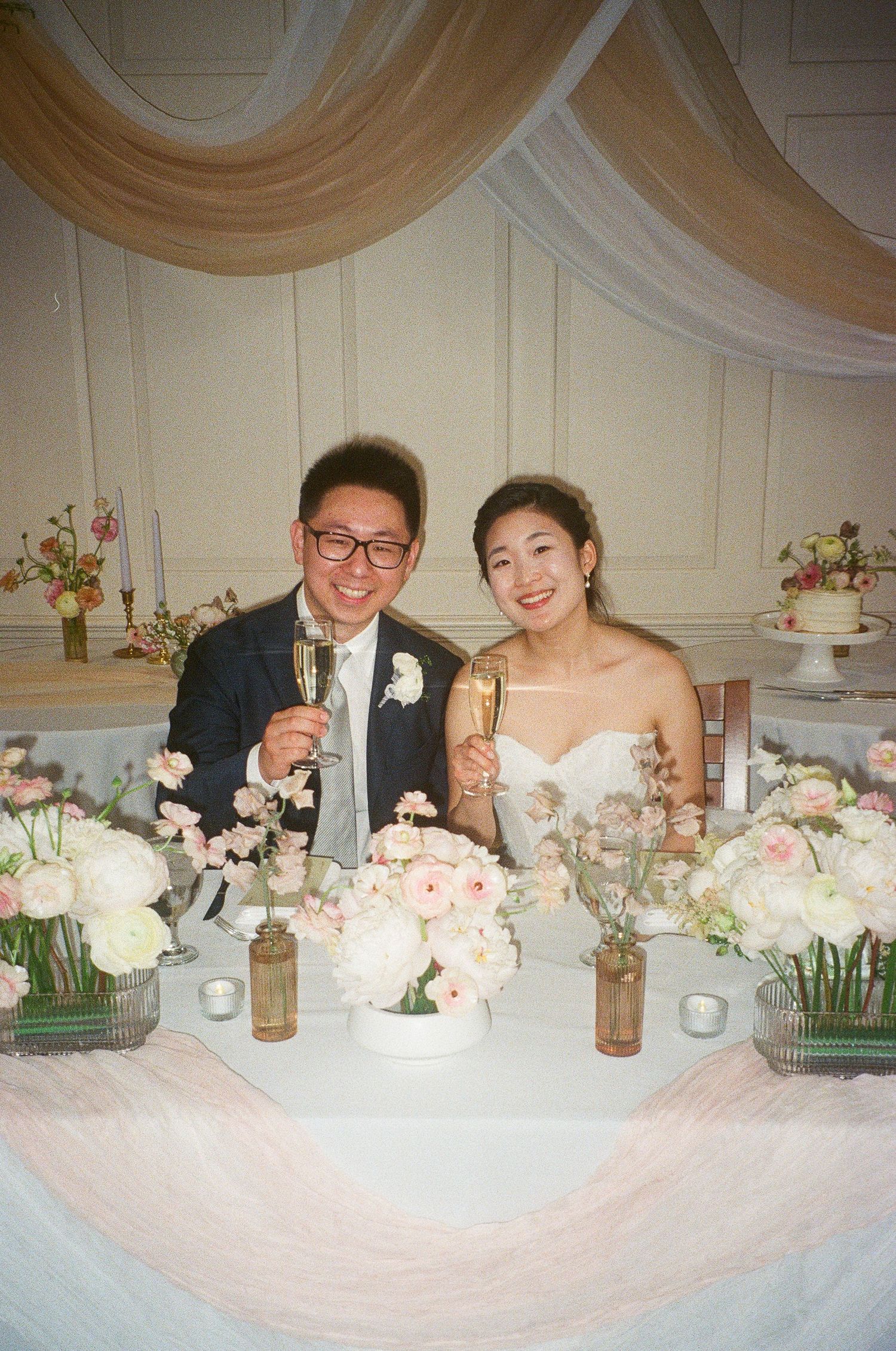 Elegant wedding reception table with blush floral centerpieces and romantic candlelight decor.