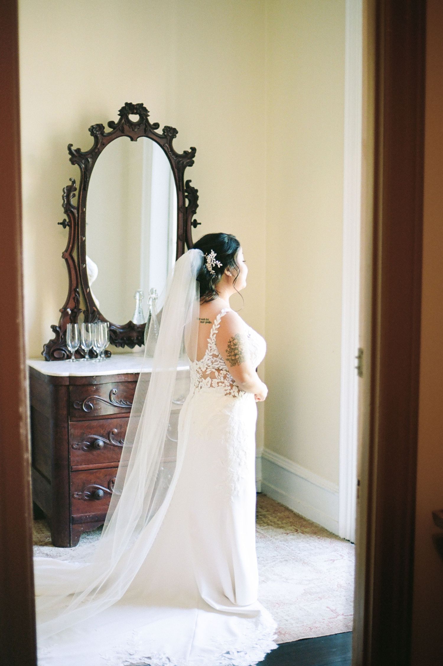 Wedding gown with flowing veil reflected in vintage mirrors.